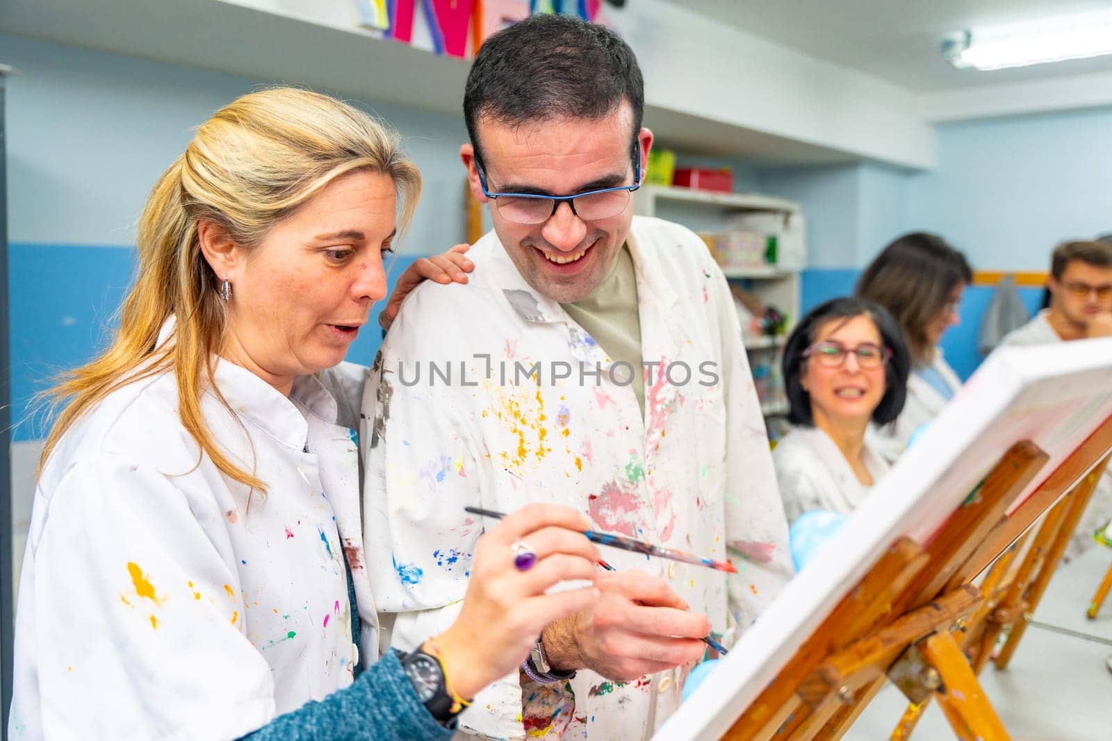 Instructor helping a disabled man during painting class by Huizi