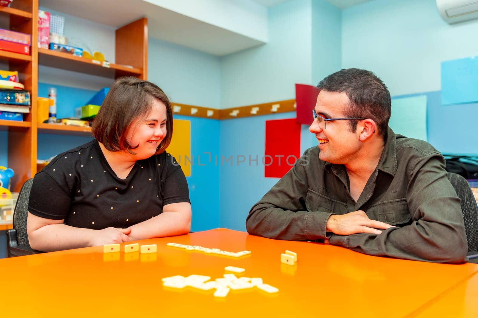 Woman with down syndrome and disabled man playing board games by Huizi