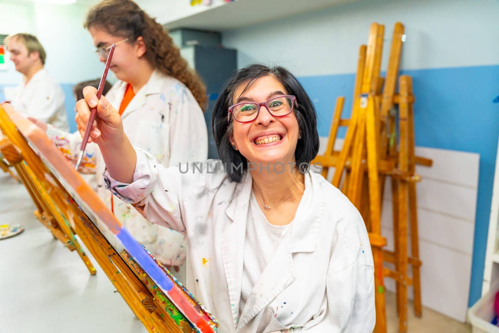 Portrait of an adult excited disabled woman smiling at camera during a painting class