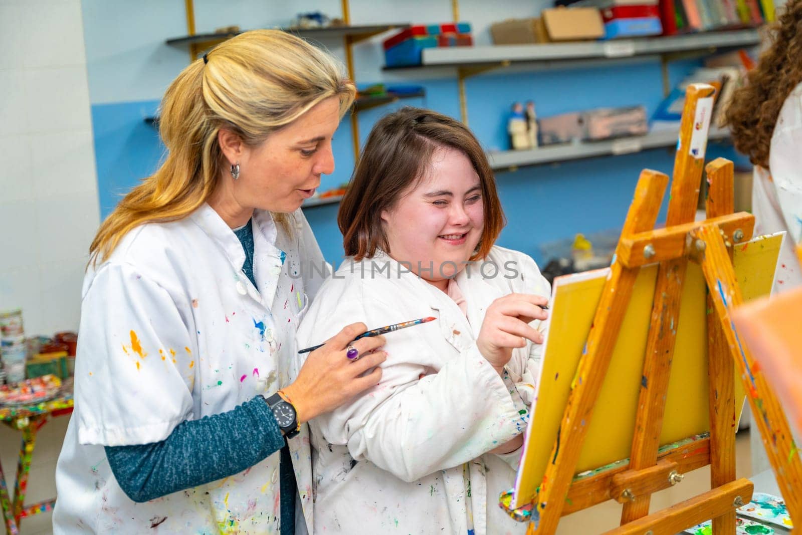 Teacher helping a woman with down syndrome during painting class by Huizi
