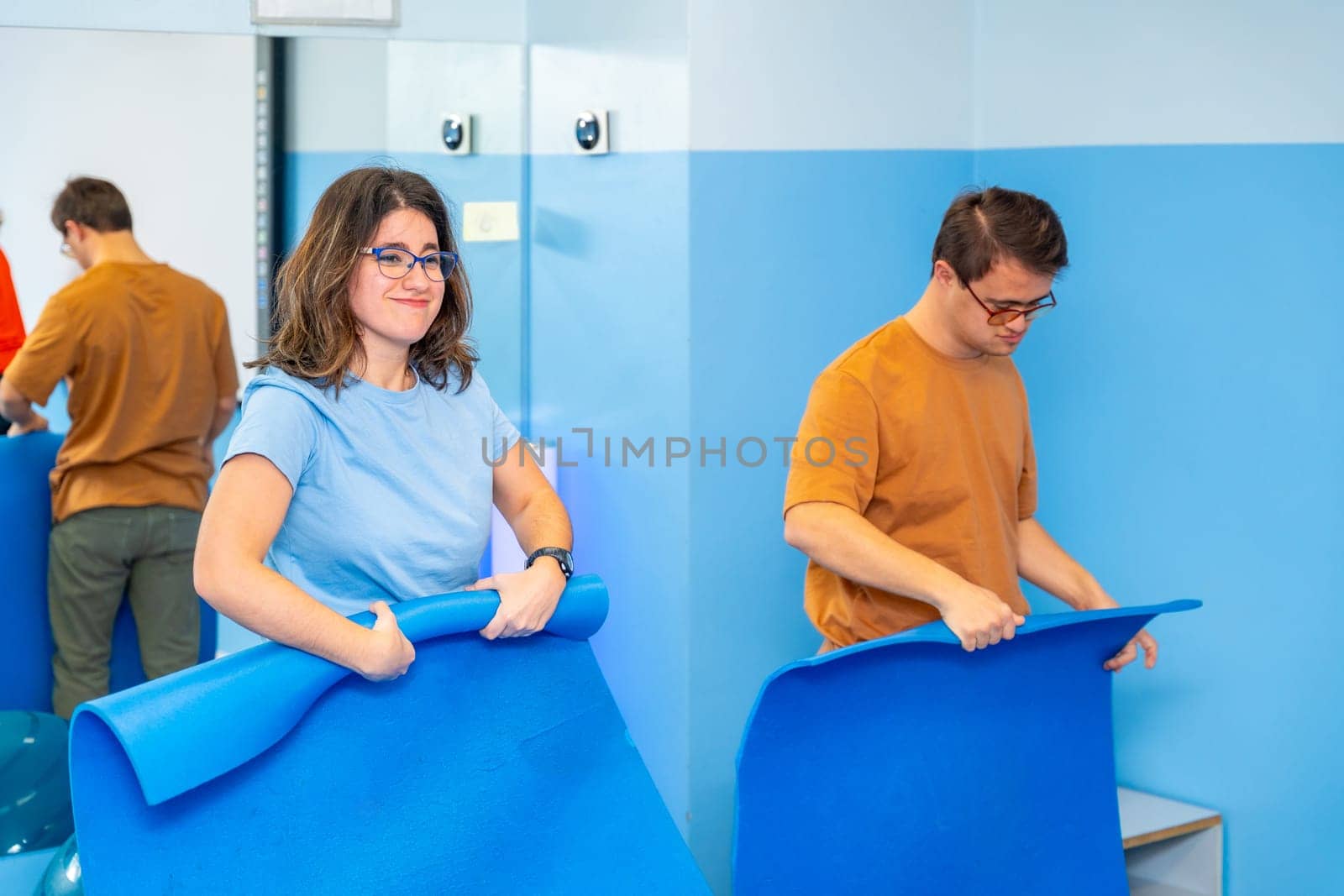 Group of people with special needs picking up the mats after a yoga class