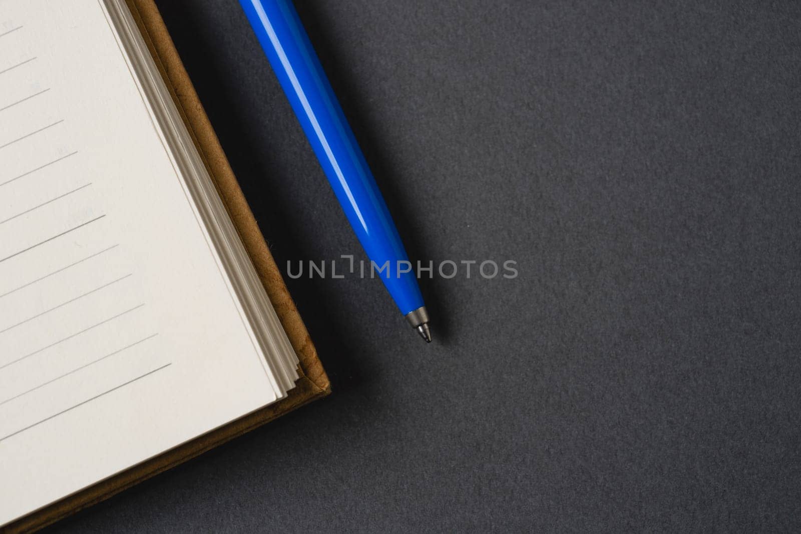 Ballpoint pen made of blue plastic and metal standing on lined notebook