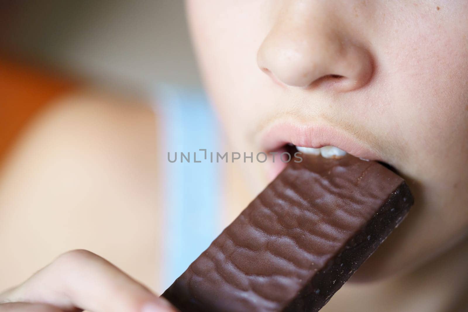 From above closeup of crop anonymous teenage girl biting nutritious protein bar at home