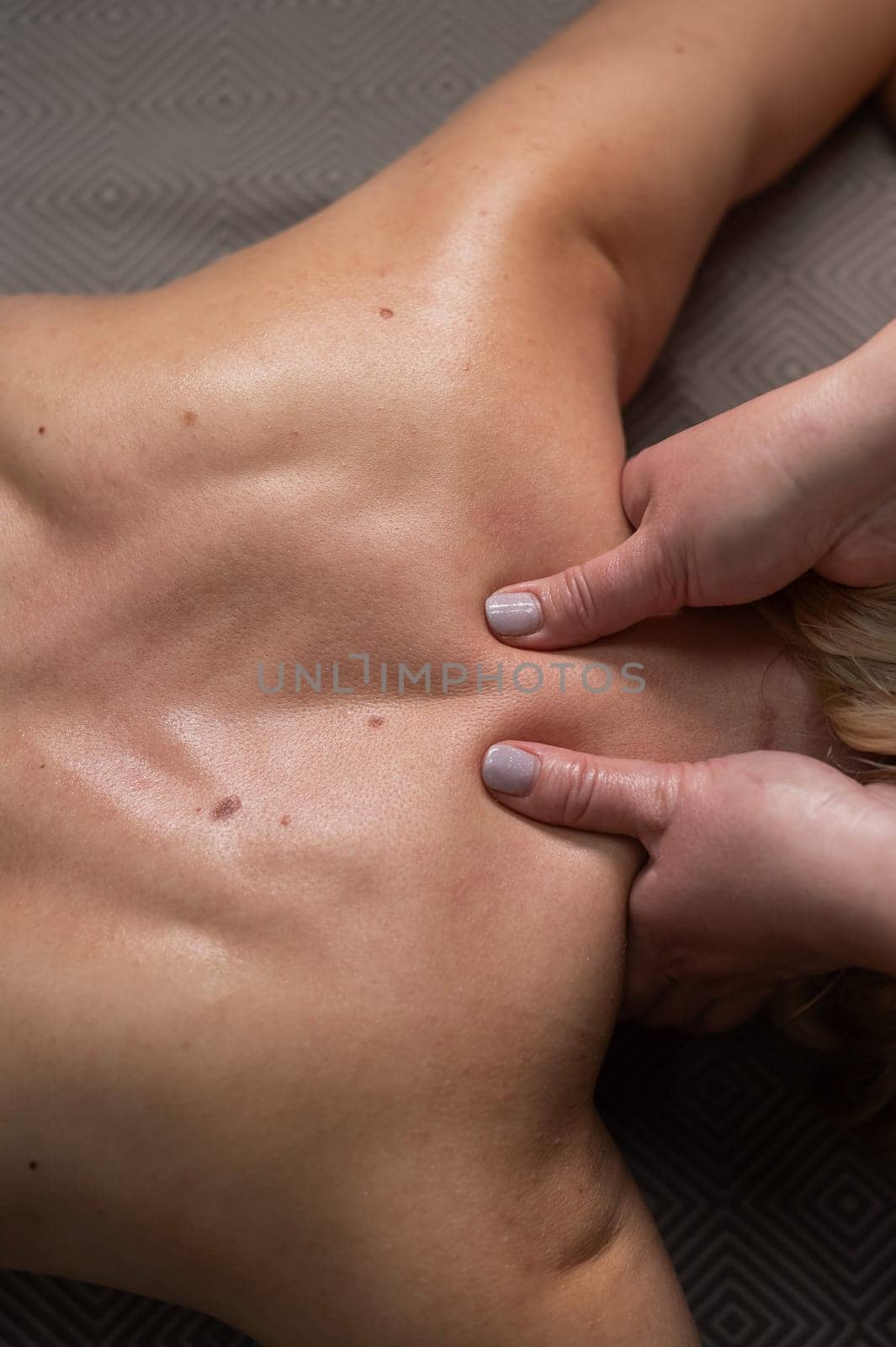 Top view of a woman undergoing a cervical-neck massage. Vertical photo. by mrwed54