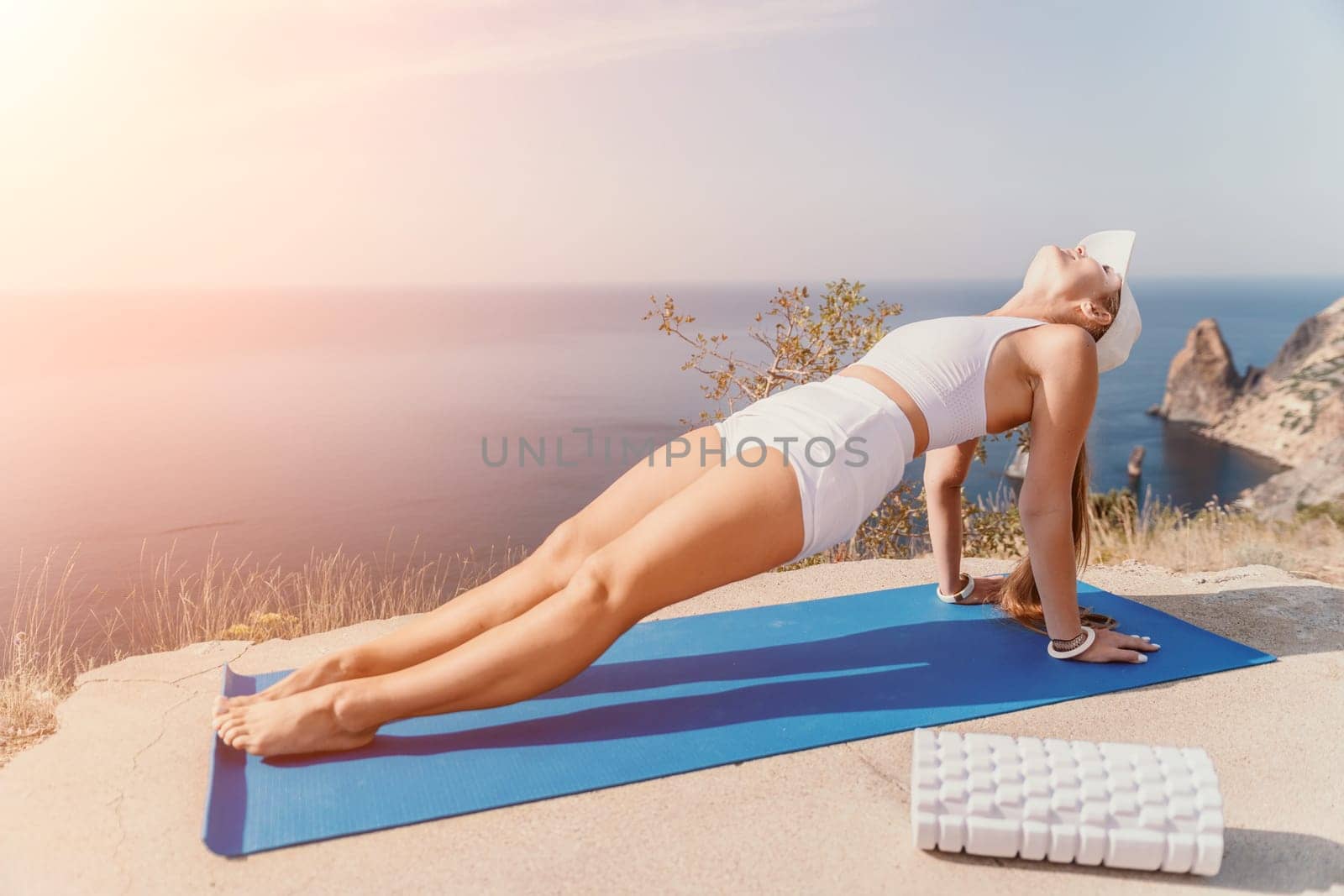 Fitness woman sea. Outdoor workout on yoga mat roller in park near to ocean beach. Female fitness pilates yoga routine concept. Healthy lifestyle. Happy fit woman exercising with rubber band in park. by panophotograph