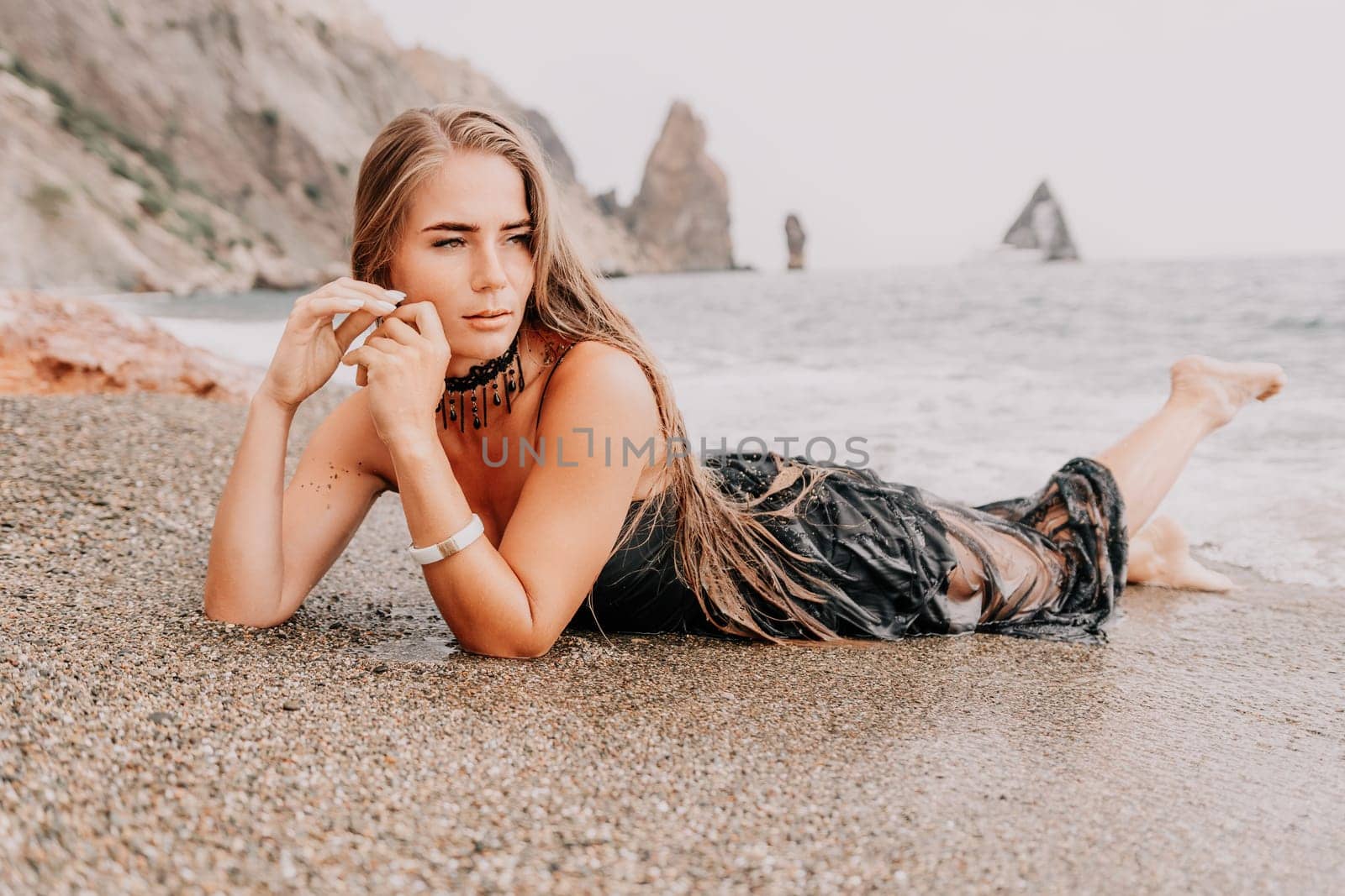 Woman travel sea. Young Happy woman in a long red dress posing on a beach near the sea on background of volcanic rocks, like in Iceland, sharing travel adventure journey