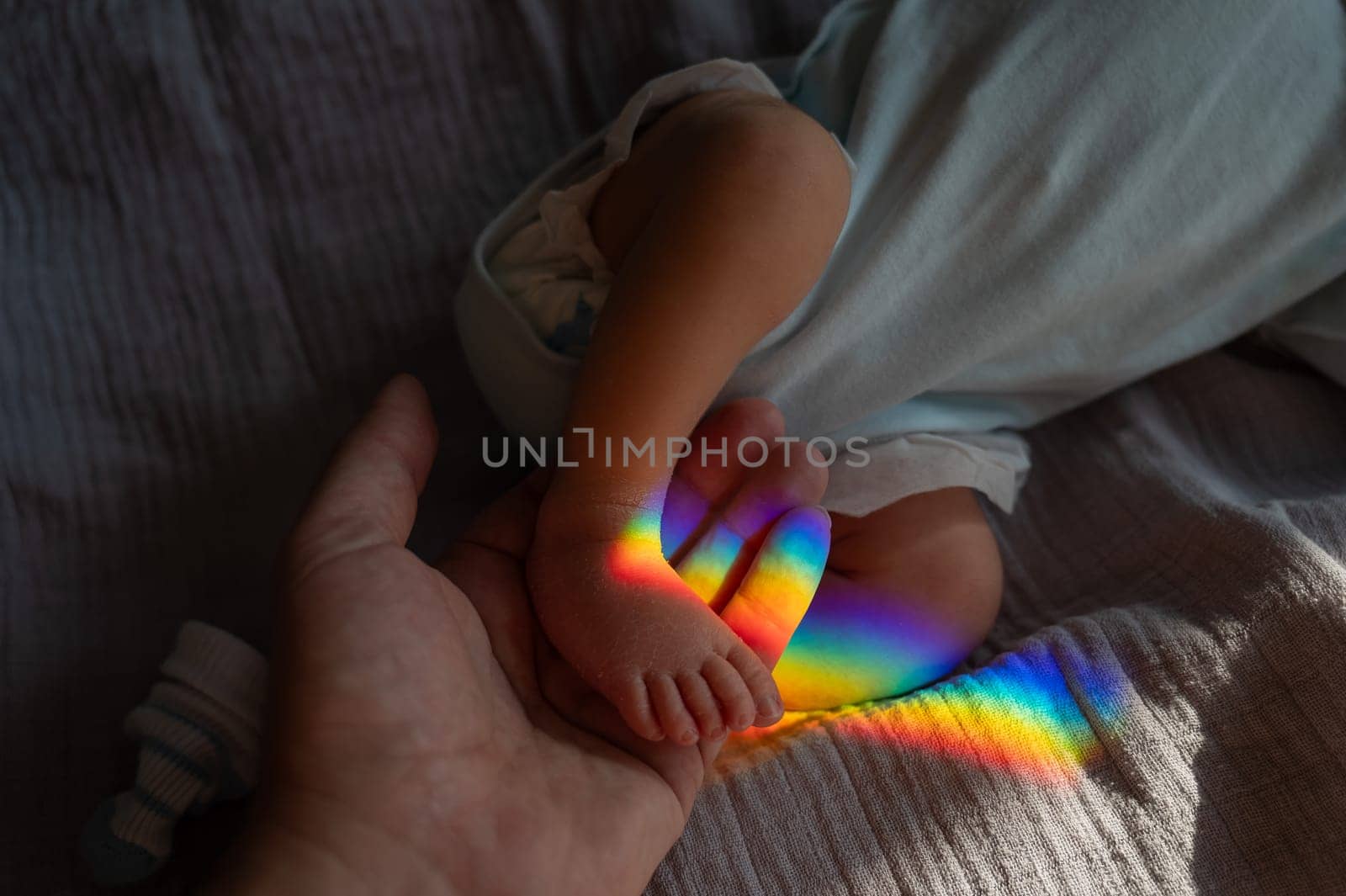 A man holds his newborn son by the leg. Beam of light through a prism. by mrwed54