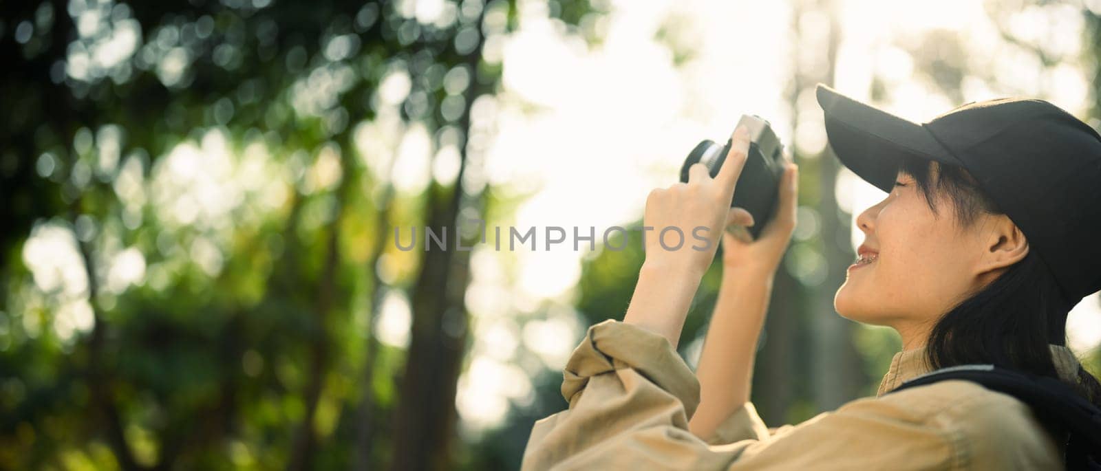 Panoramic photo of smiling female traveller taking photo with camera in nature. Holiday, travel and lifestyle concept.