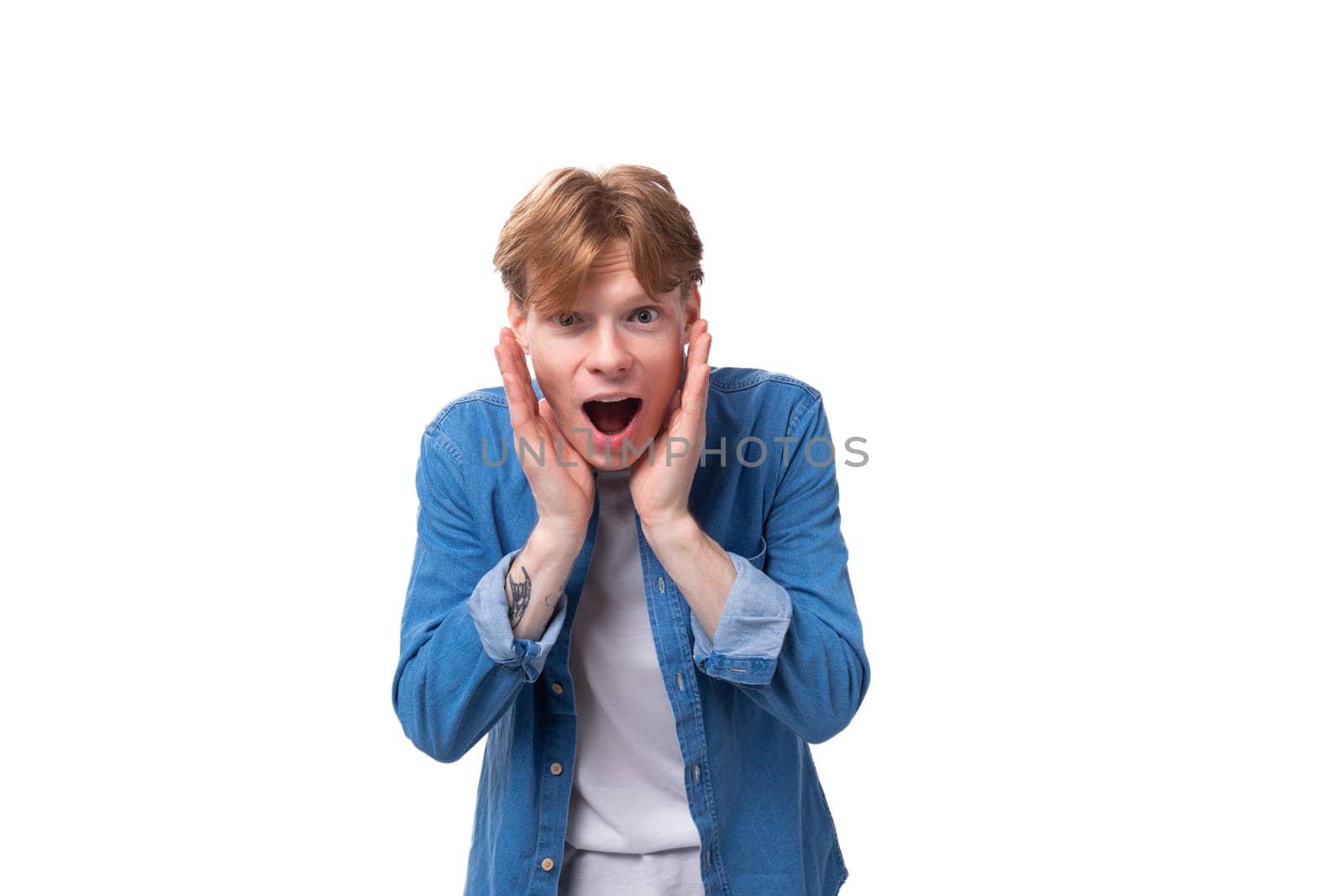 portrait of a surprised caucasian red-haired guy in a denim blue shirt and a white t-shirt by TRMK