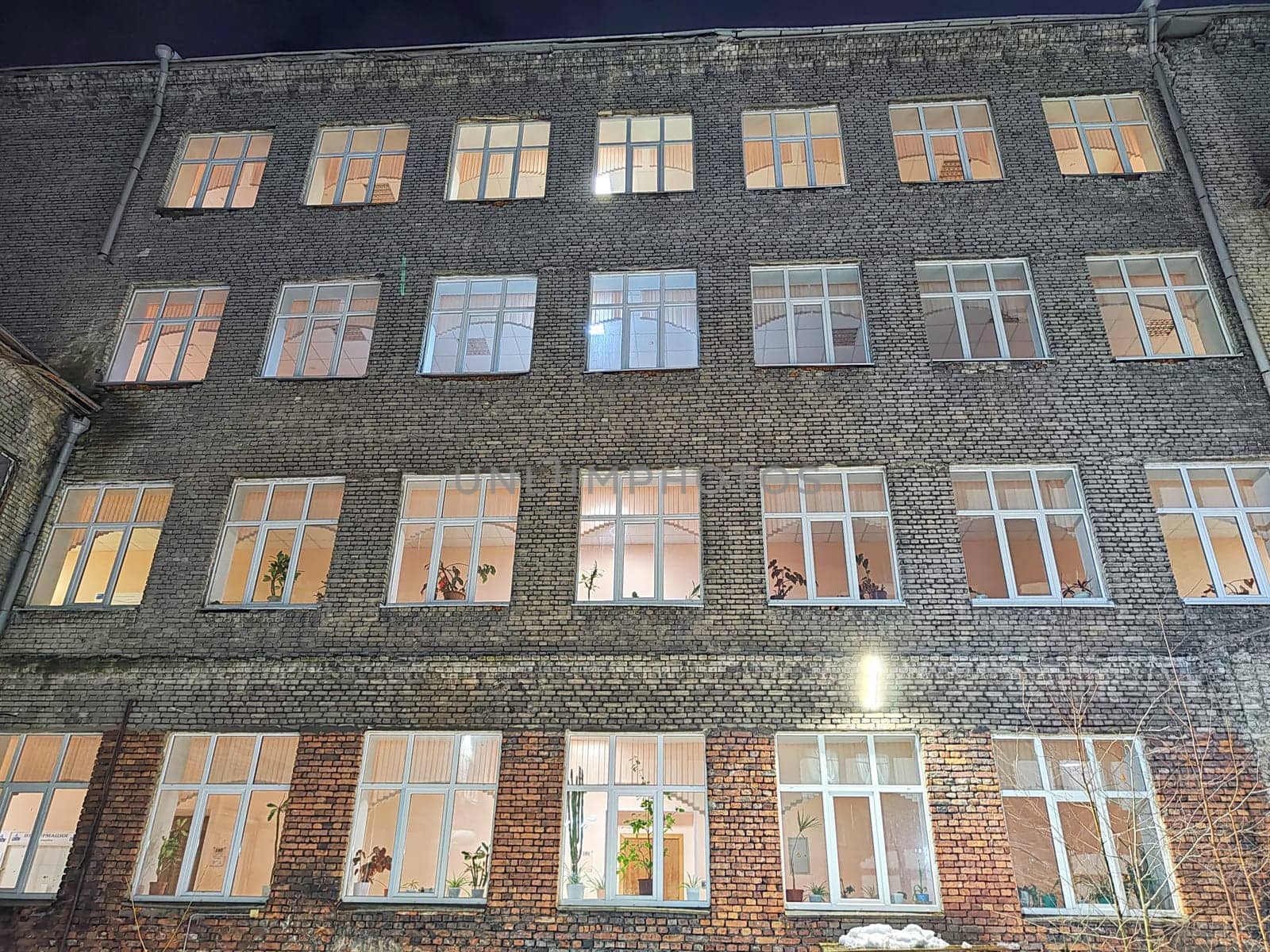 Lit windows of brick office building after dark. Illuminated Office Building at Nighttime