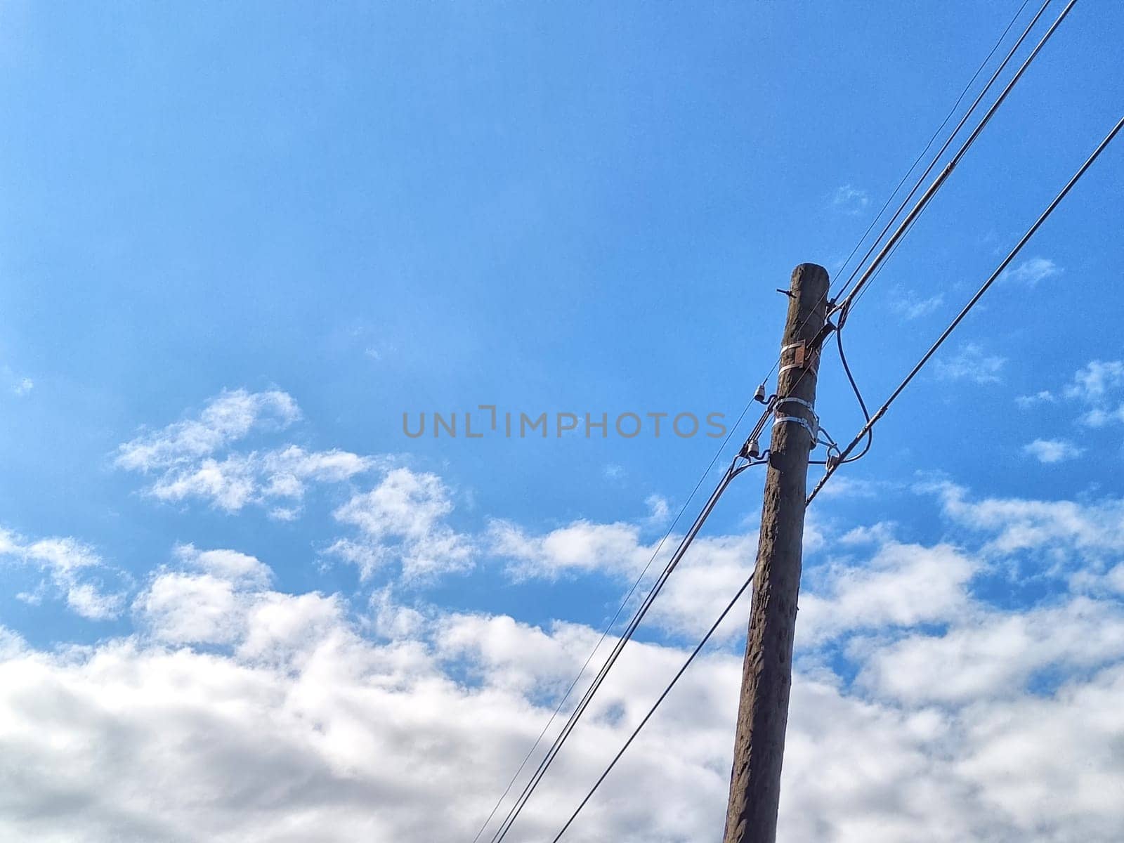 Old power line pole against blue sky in a nice sunny day