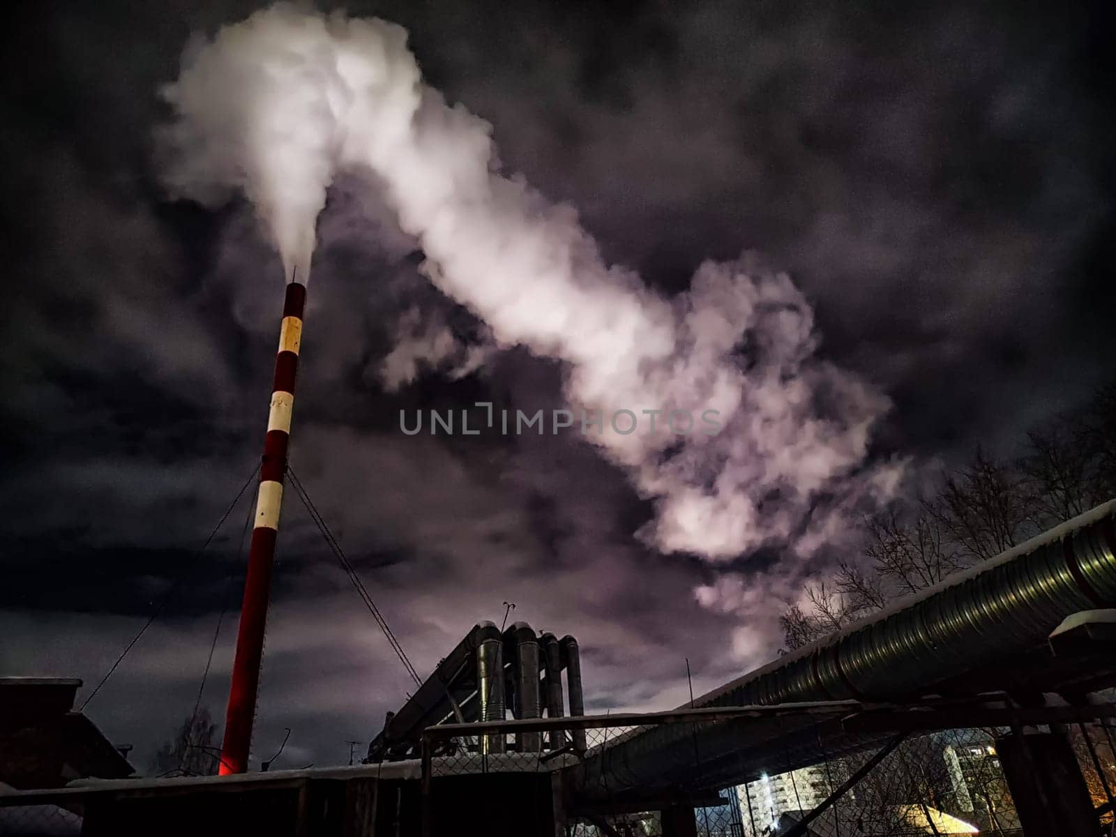 Winter night industrial landscape. Coal-fired power station with smoking chimneys against dramatic dark sky. Carbon dioxide CO2 emissions as primary driver of global climate change. Air pollution