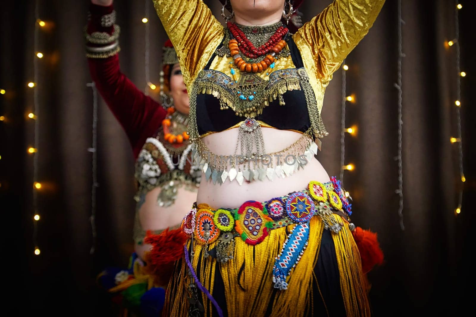 Diverse group of women wearing vibrant, multi-colored dress and tassels dancing tribal on ethnic celebratory event