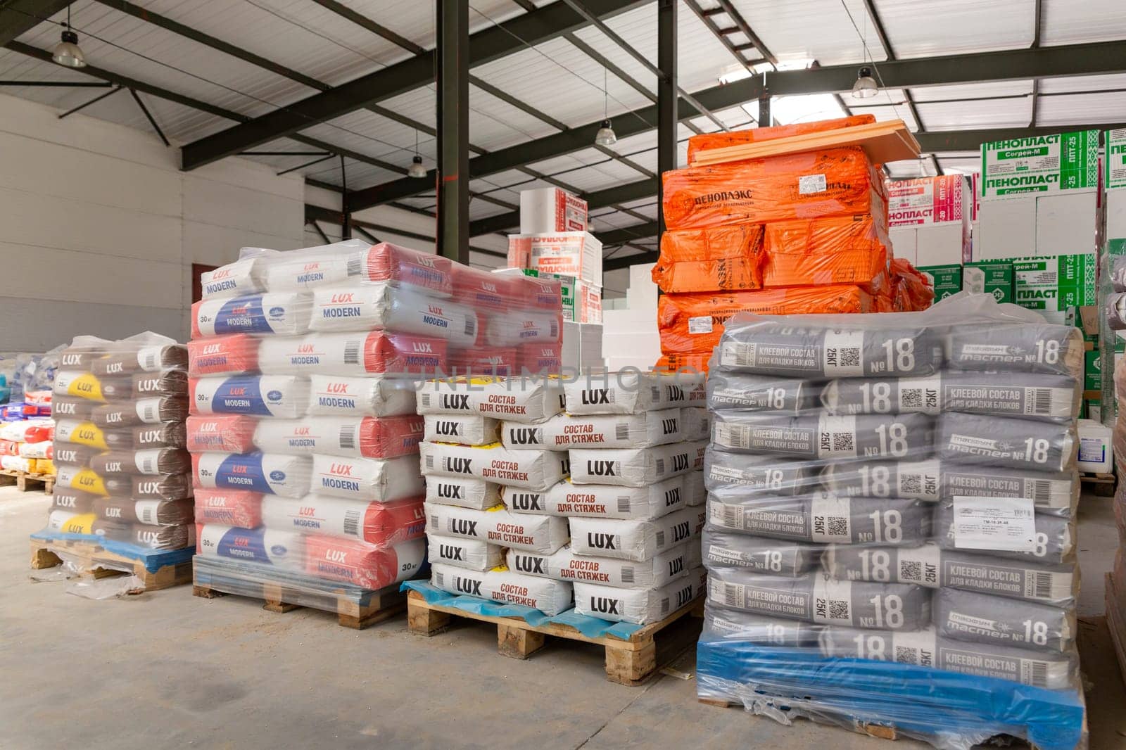 Belarus, Grodno - June 02, 2023: Heap of industrial bags with adhesive for thermal insulation, building materials at a construction market Sogrey-M