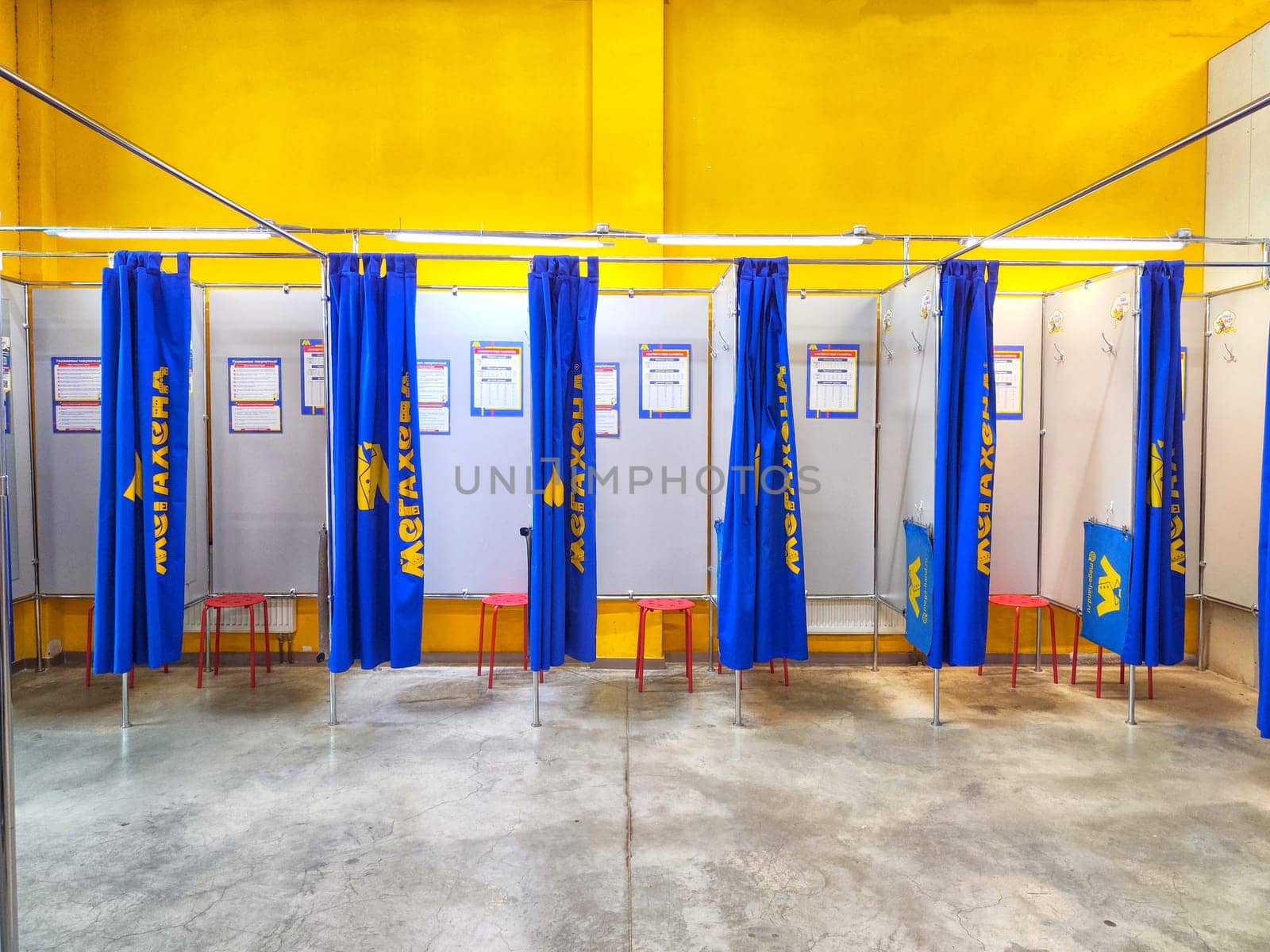 Kirov, Russia - January 04, 2024: Fitting Booths at Meghand Store With Blue Curtains and Red Stools. Blue curtained changing areas with red stools at Megahand store