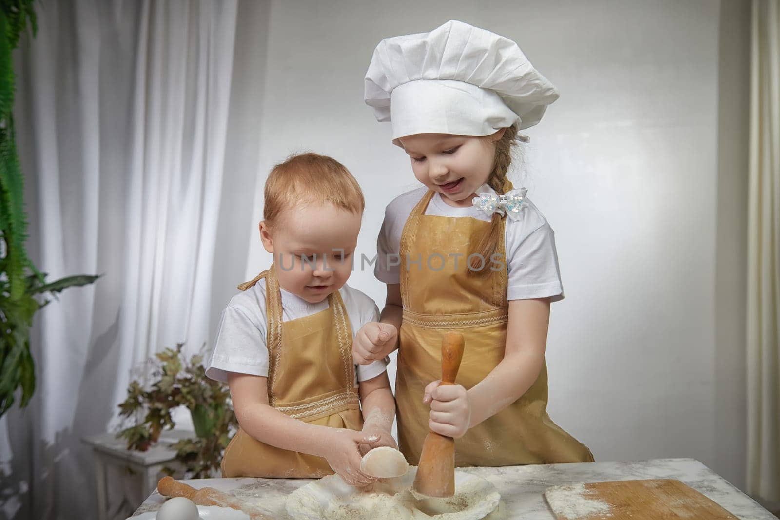 Cute oriental family with small brother and sister cooking in kitchen on Ramadan, Kurban-Bairam, Eid al-Adha. Funny children boy and girl at cook photo shoot. Pancakes, Maslenitsa, Easter by keleny