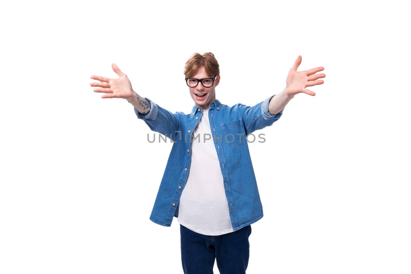 young joyful surprised red-haired guy dressed in a blue shirt wears glasses on a white background with copy space.