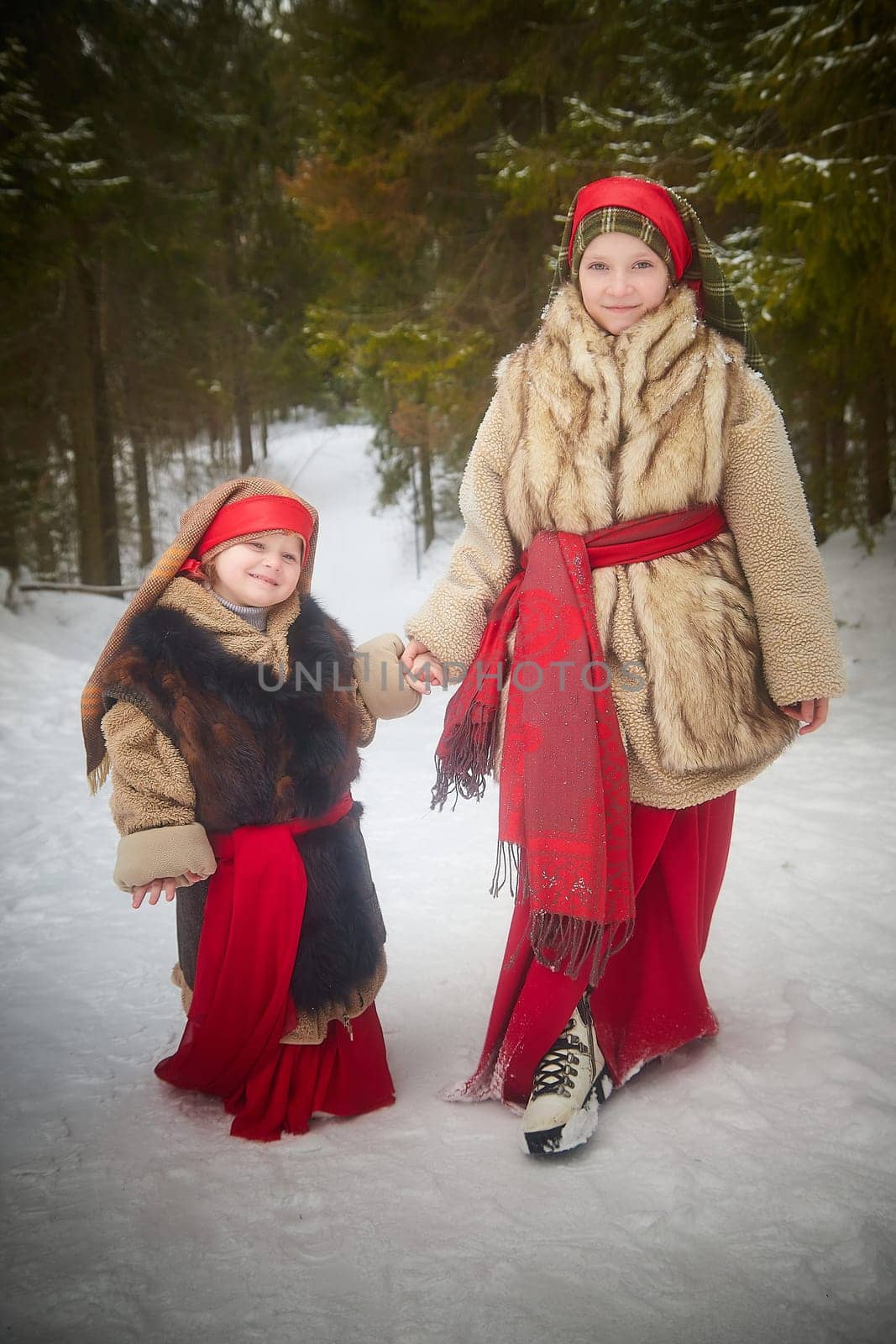 Teen and little girl in thick coat in cold winter day in forest. Medieval peasant sisters collecting firewood. Photoshoot in stile of Christmas fairy tale by keleny