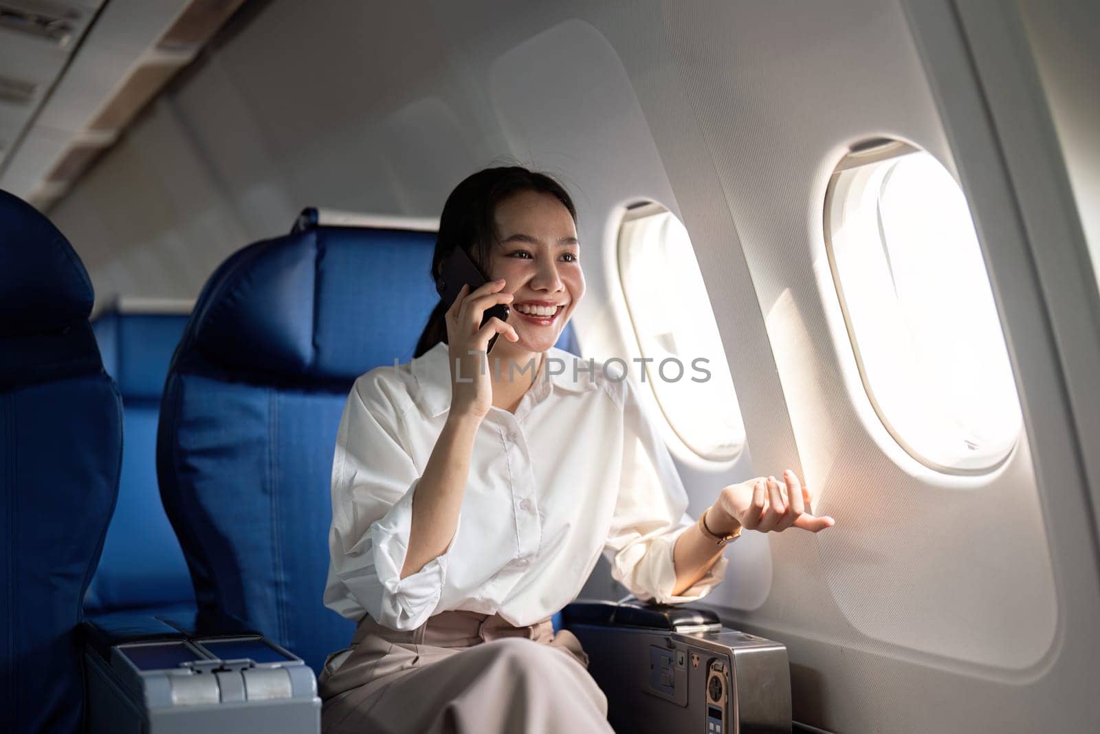 Traveling and technology. Flying at first class. Young business woman passenger using smartphone while sitting in airplane flight by nateemee