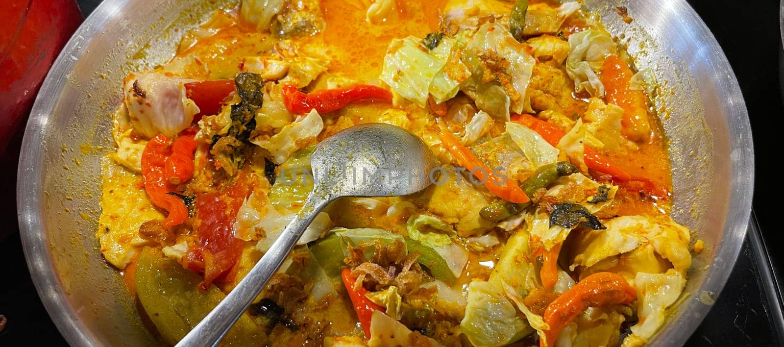 Selective focus Indonesian traditional dish mangut fish, made from smoked fish, cooked with coconut milk sauce mixed with spices, tomato, turmeric, and chillies with various seasonings