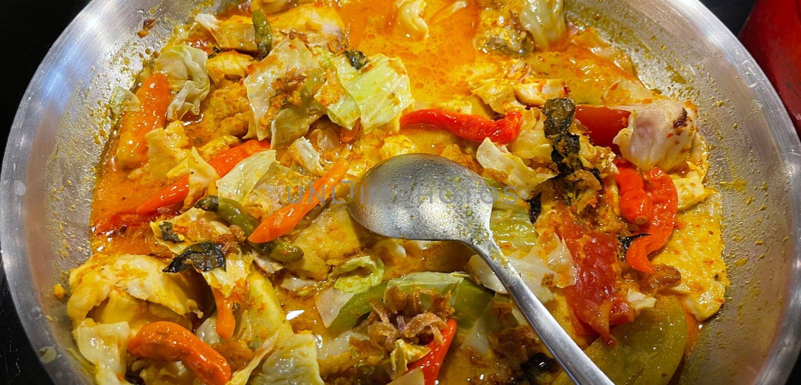 Selective focus Indonesian traditional dish mangut fish, made from smoked fish, cooked with coconut milk sauce mixed with spices, tomato, turmeric, and chillies with various seasonings