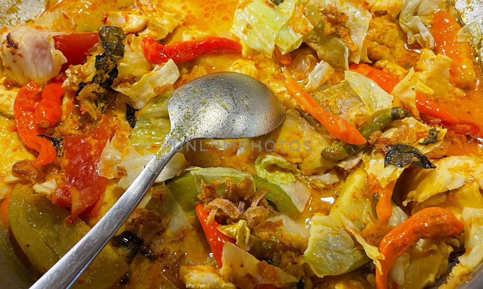 Selective focus Indonesian traditional dish mangut fish, made from smoked fish, cooked with coconut milk sauce mixed with spices, tomato, turmeric, and chillies with various seasonings