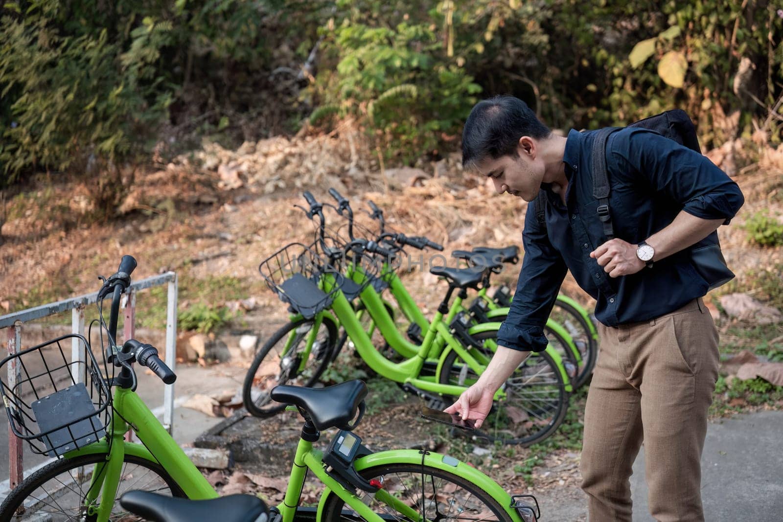 Energy reduction concept A young businessman rides a public bicycle to work in order to reduce pollution..