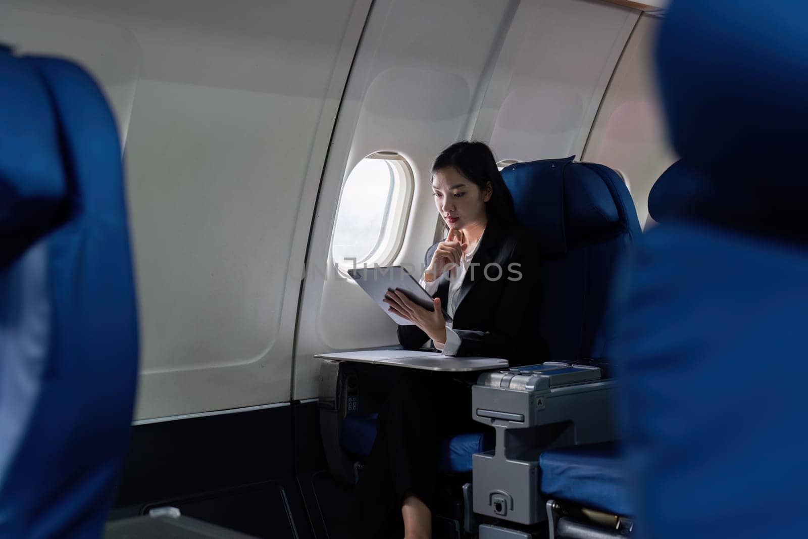 Beautiful Asian businesswoman working with tablet in aeroplane. working, travel, business concept by itchaznong