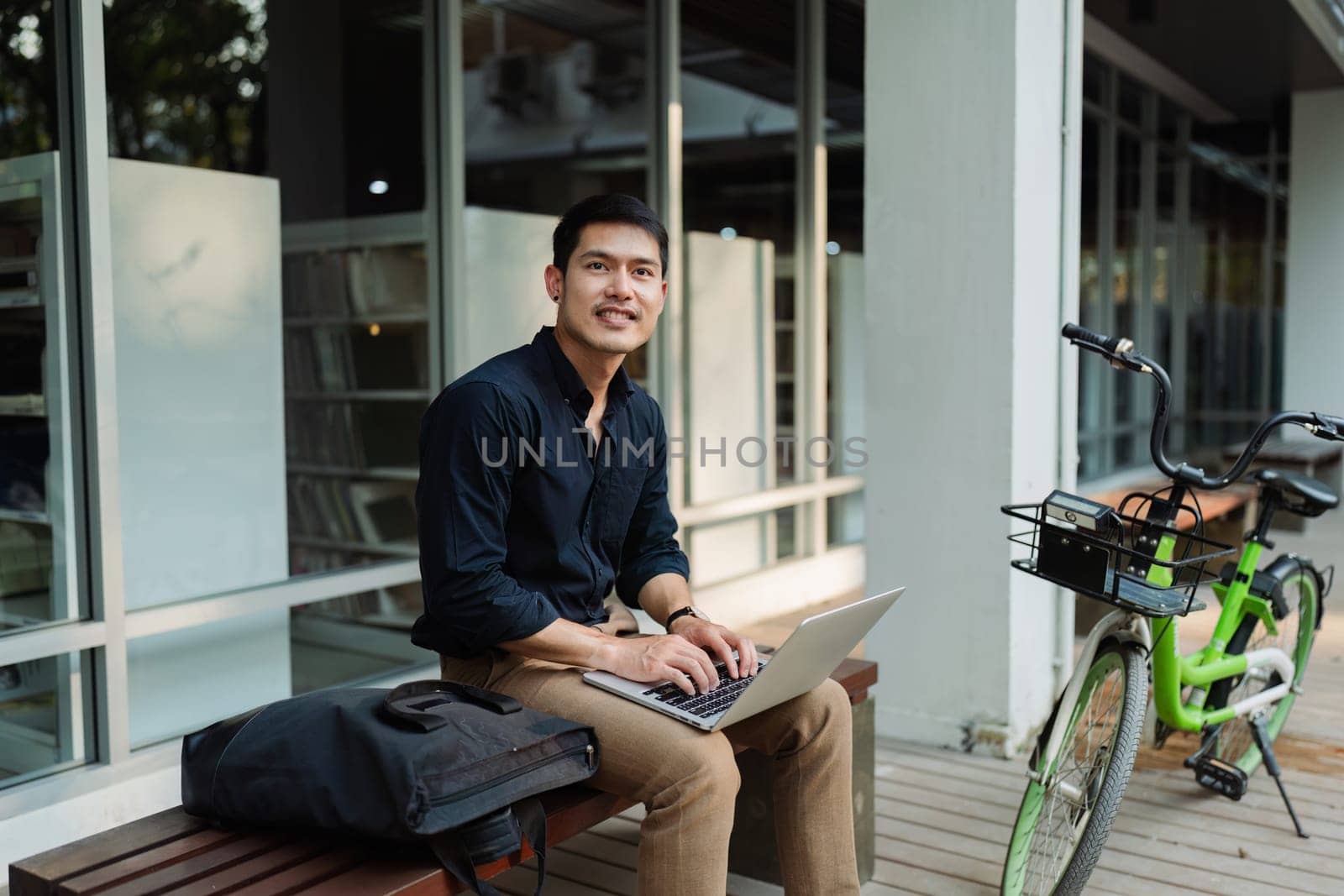 business man sitting on bench and working remotely on project with laptop.