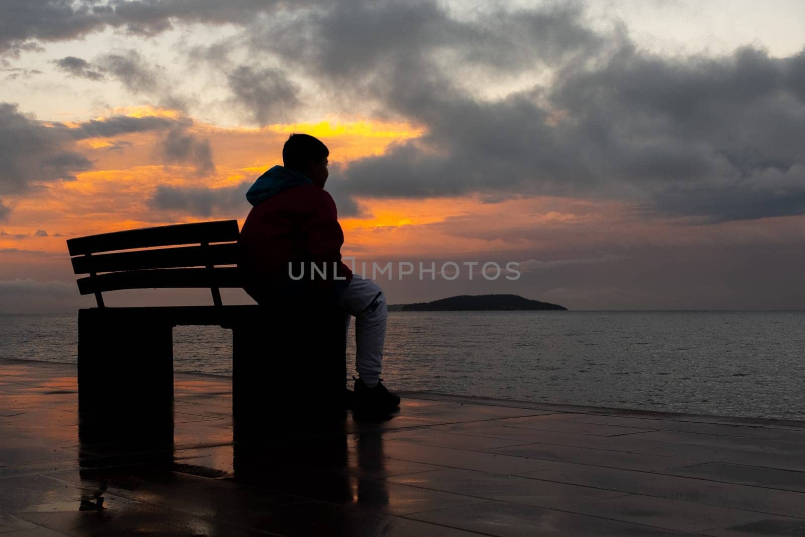 Sitting on bench by ocean at sunset, watching liquid horizon blend with dusk sky by senkaya