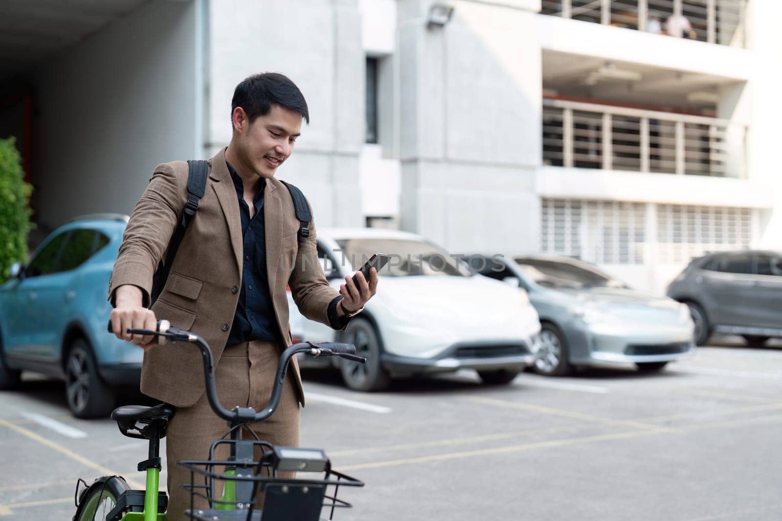 Asian businessman in a suit is riding a bicycle on the city streets for his morning commute to work. Eco transportation concept, sustainable lifestyle concept by nateemee