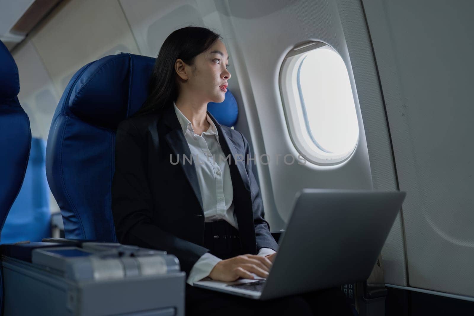 Beautiful Asian businesswoman working with laptop in aeroplane. working, travel, business concept by itchaznong