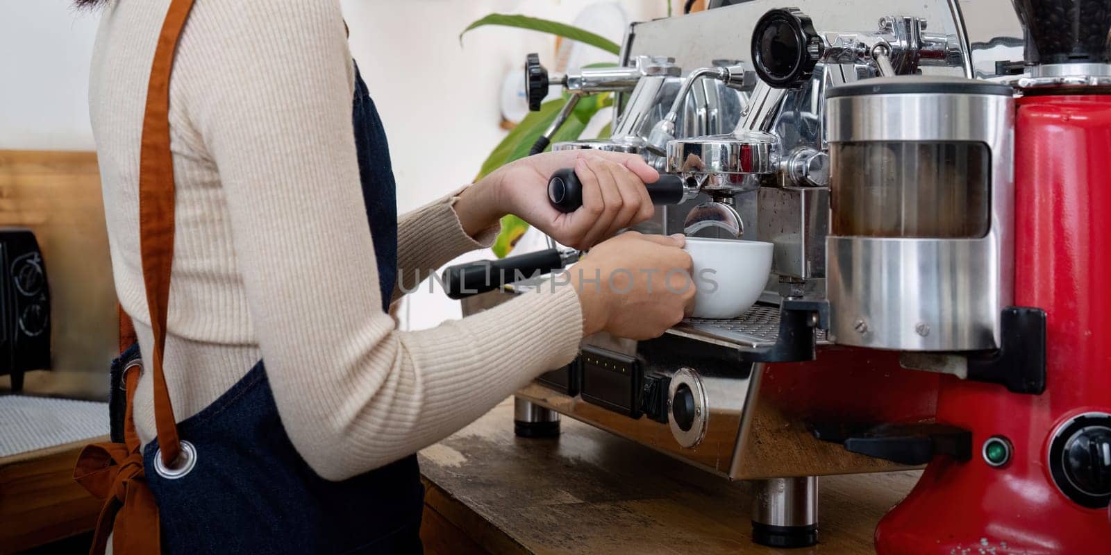 Women barista using coffee machine for making coffee in the cafe.