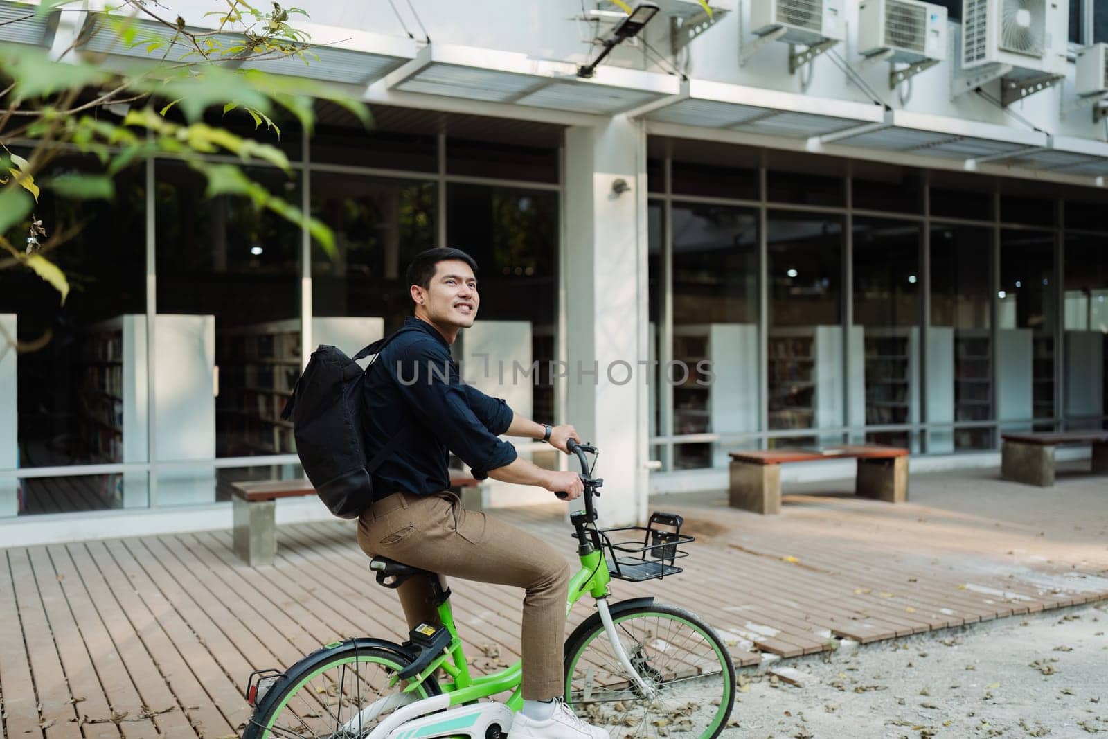 Elegant entrepreneur in smart casual cycling on bicycle track in warm sunny day area of city.