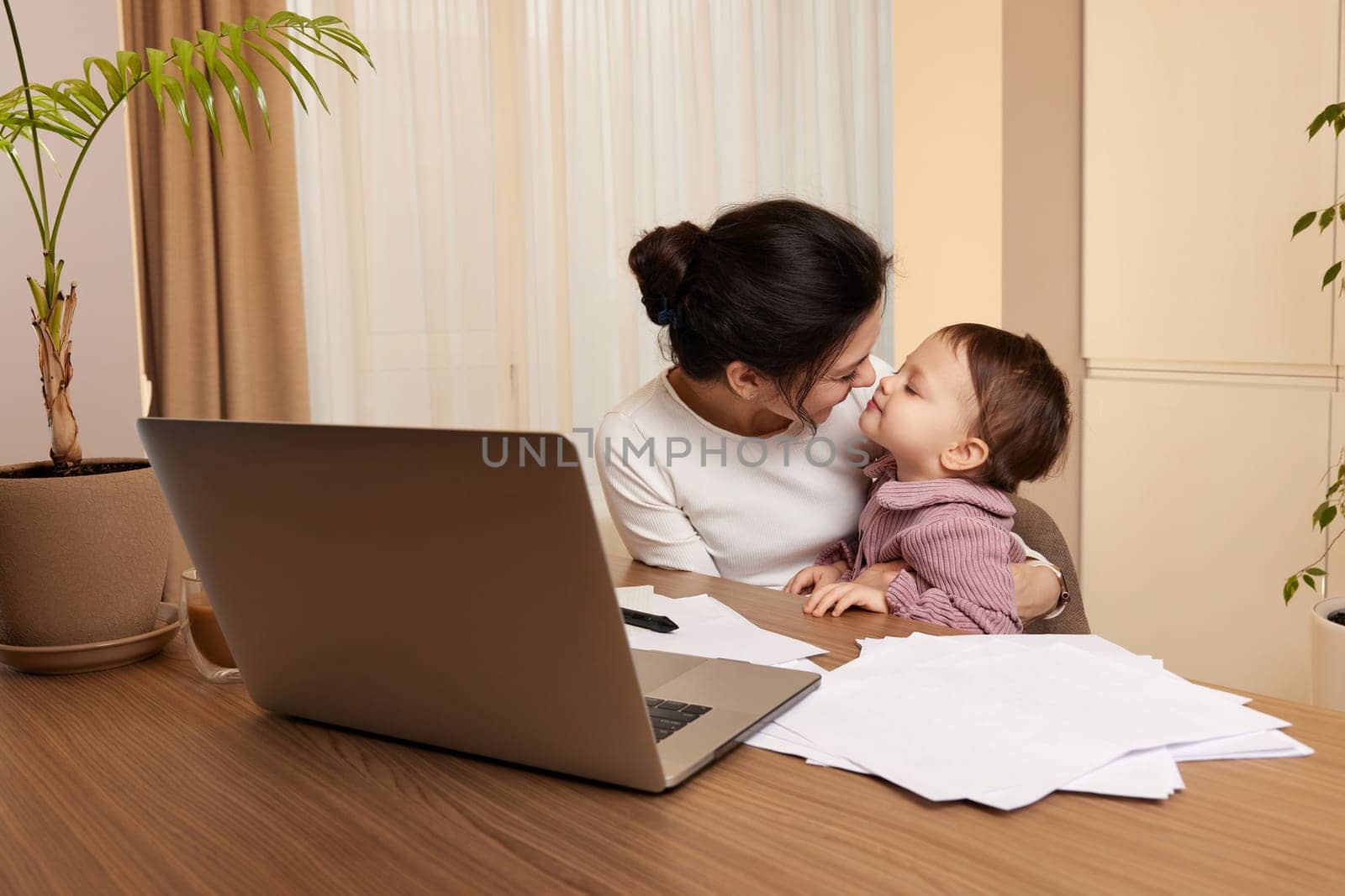 happy woman working and and playing with her baby girl at home