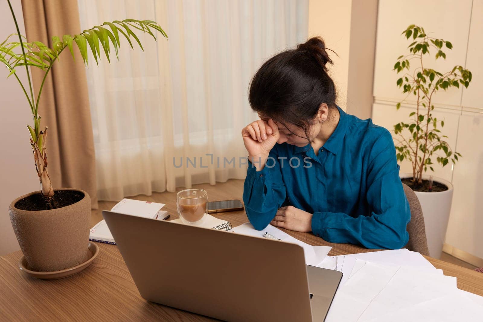 tired woman working at laptop at home by erstudio