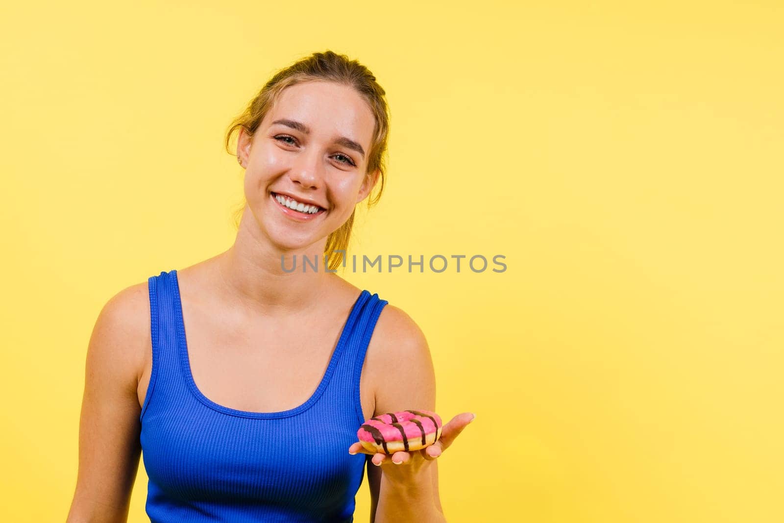 Young cute sport woman eating donut cake in studio background