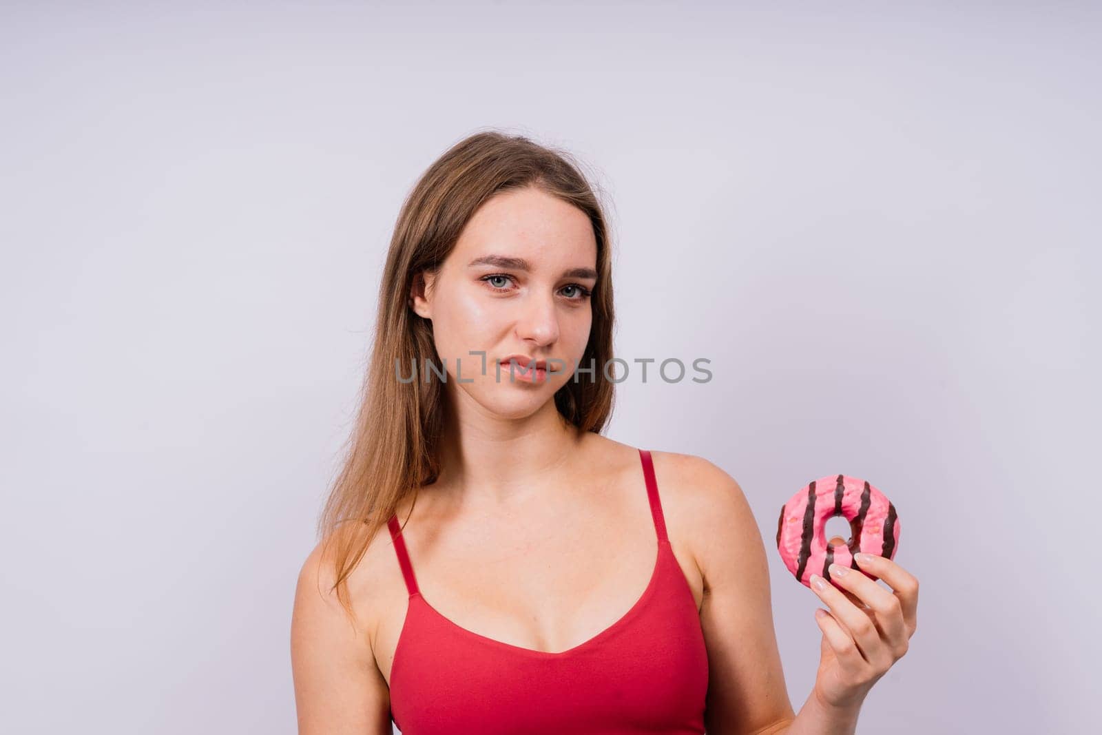 Young cute sport woman eating a donut cake in studio background by Zelenin