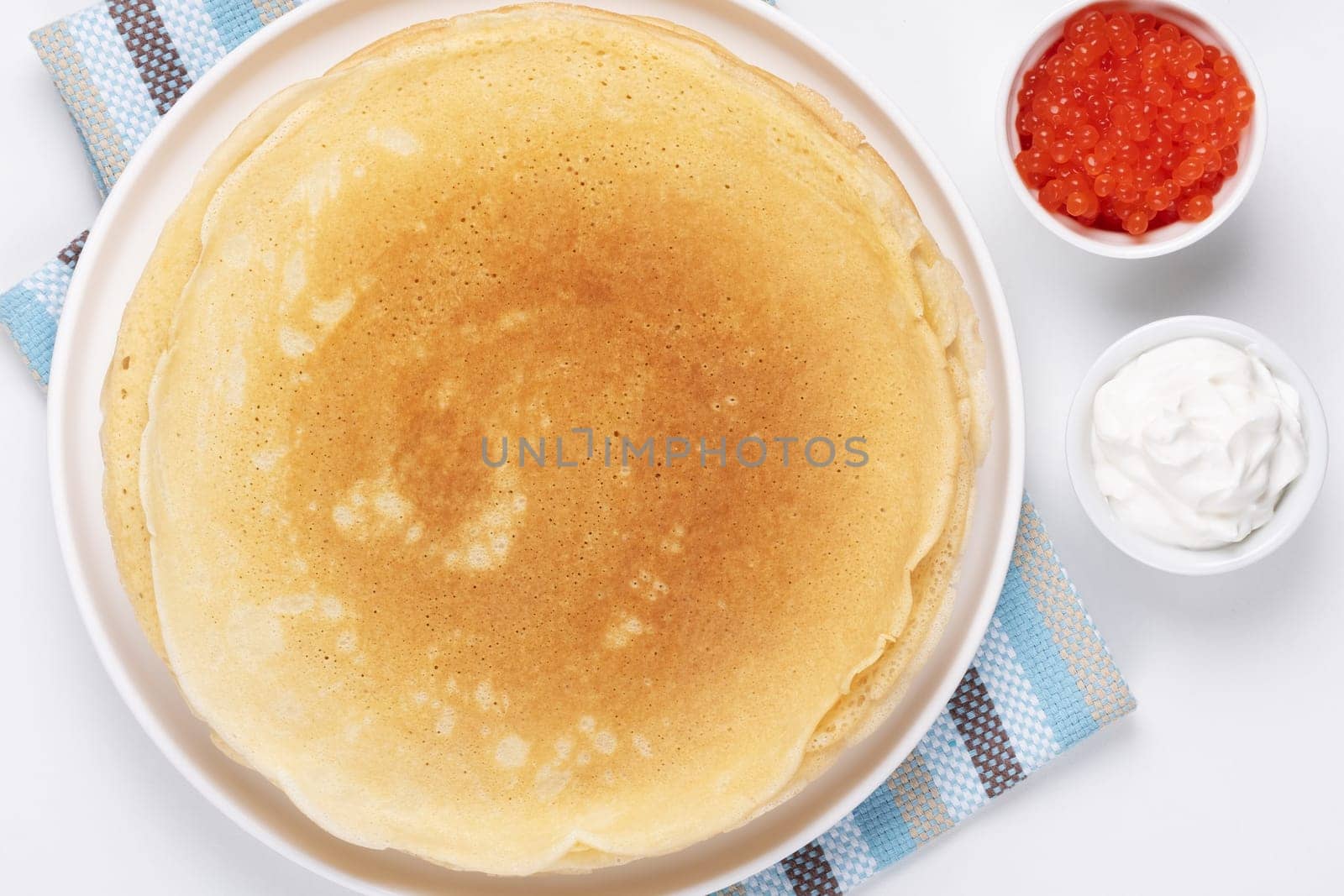 Pancakes with red caviar and sour cream, Close-up of pancakes stacked on white background by NataliPopova