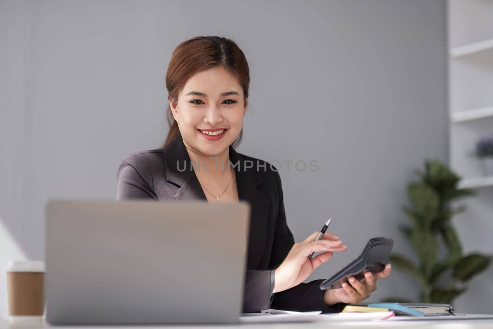 Businesswoman using laptop and mobile phone talking about work and managing company business by wichayada