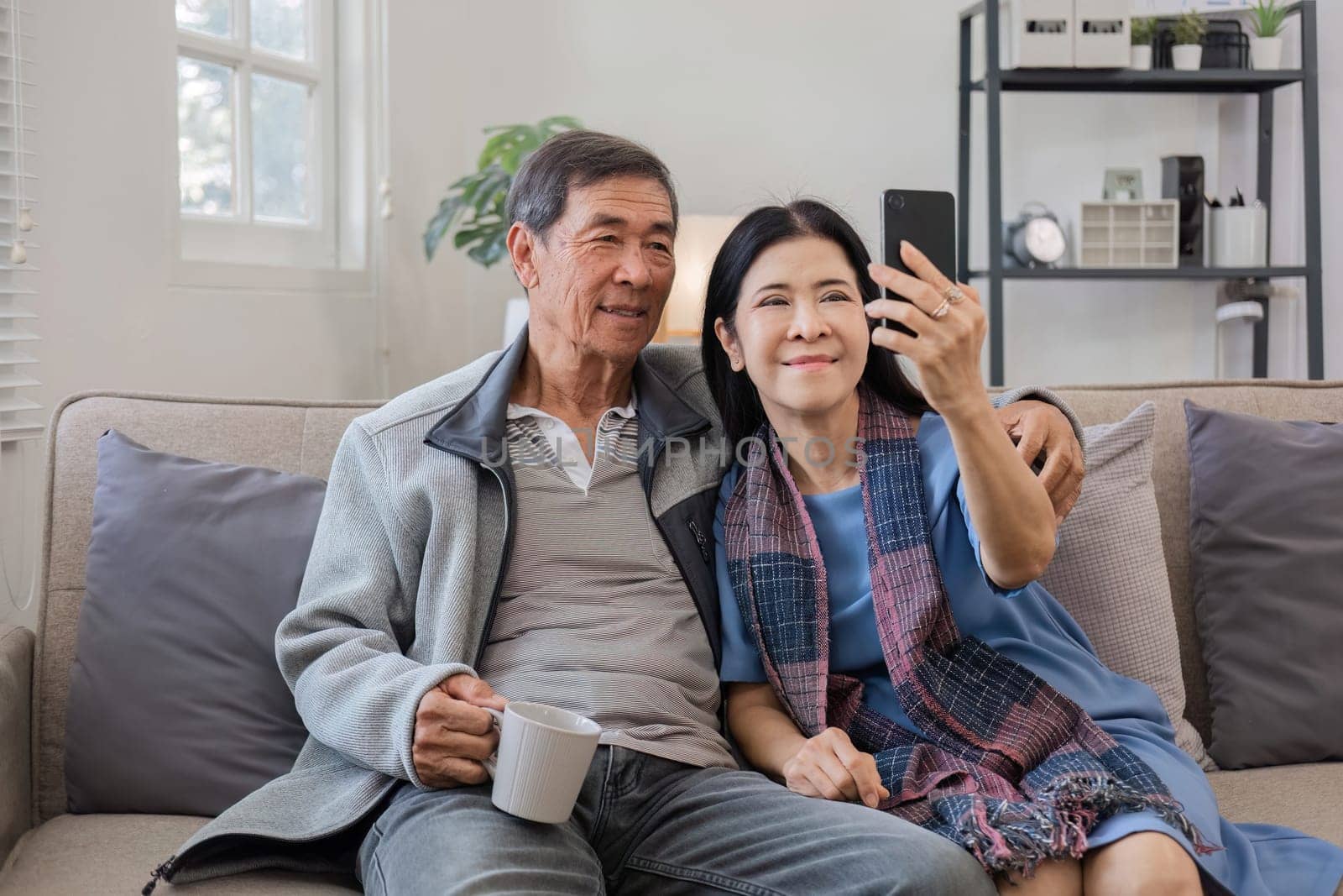 Senior couple in their 60s video chat greeting each other on vacation Have fun together on the sofa in the living room..