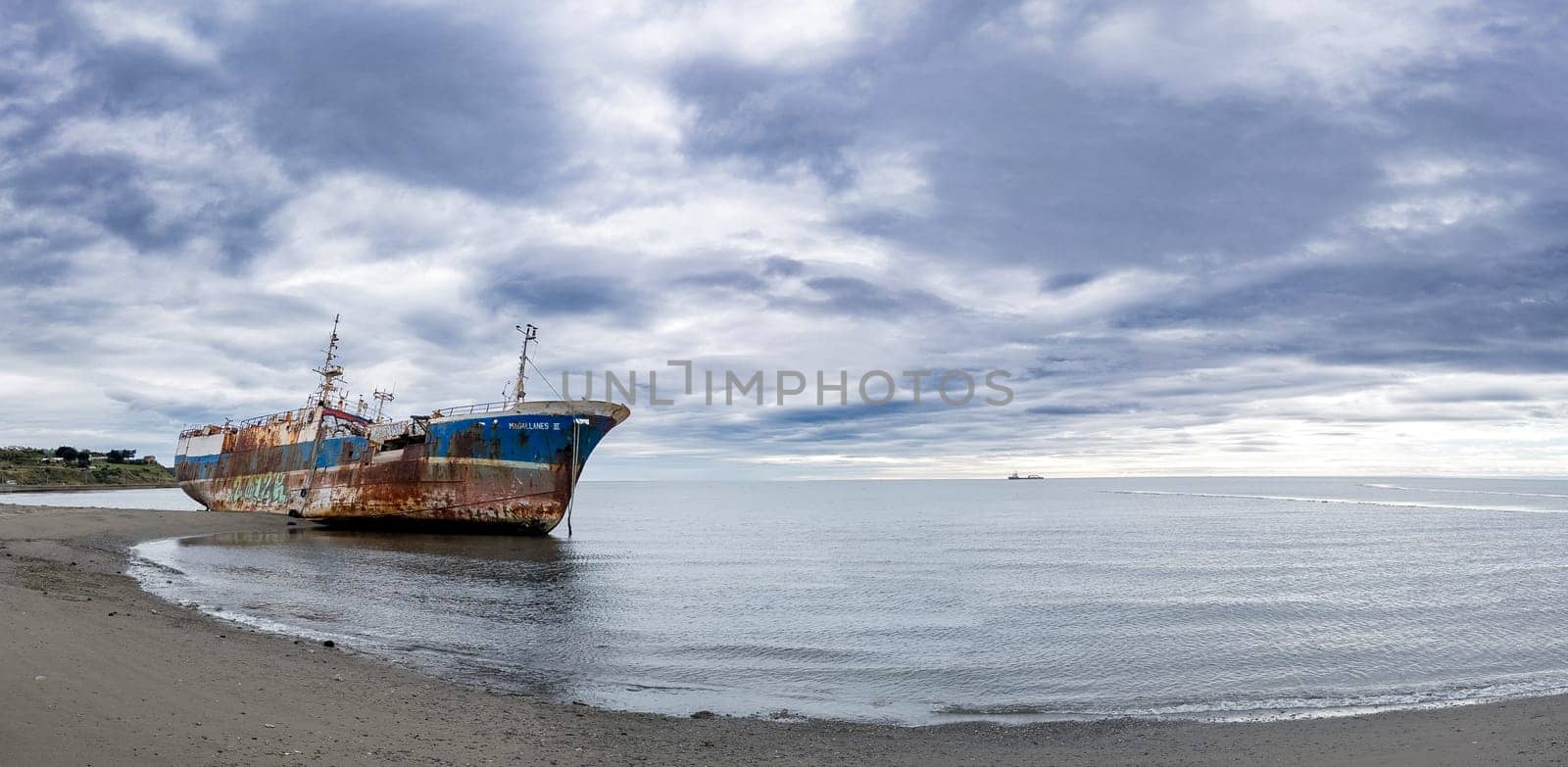 Rusted Shipwreck on Serene Beach Under Cloudy Sky by FerradalFCG