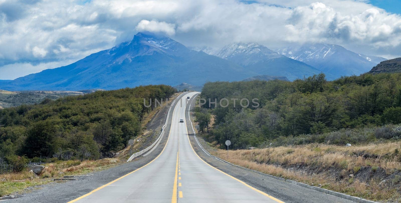 Expansive highway leads to mountains under cloudy sky.