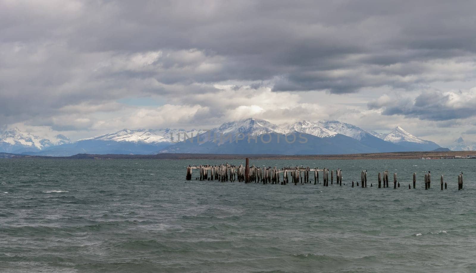 Old Pier Remnants Against a Majestic Snowy Mountain Range by FerradalFCG