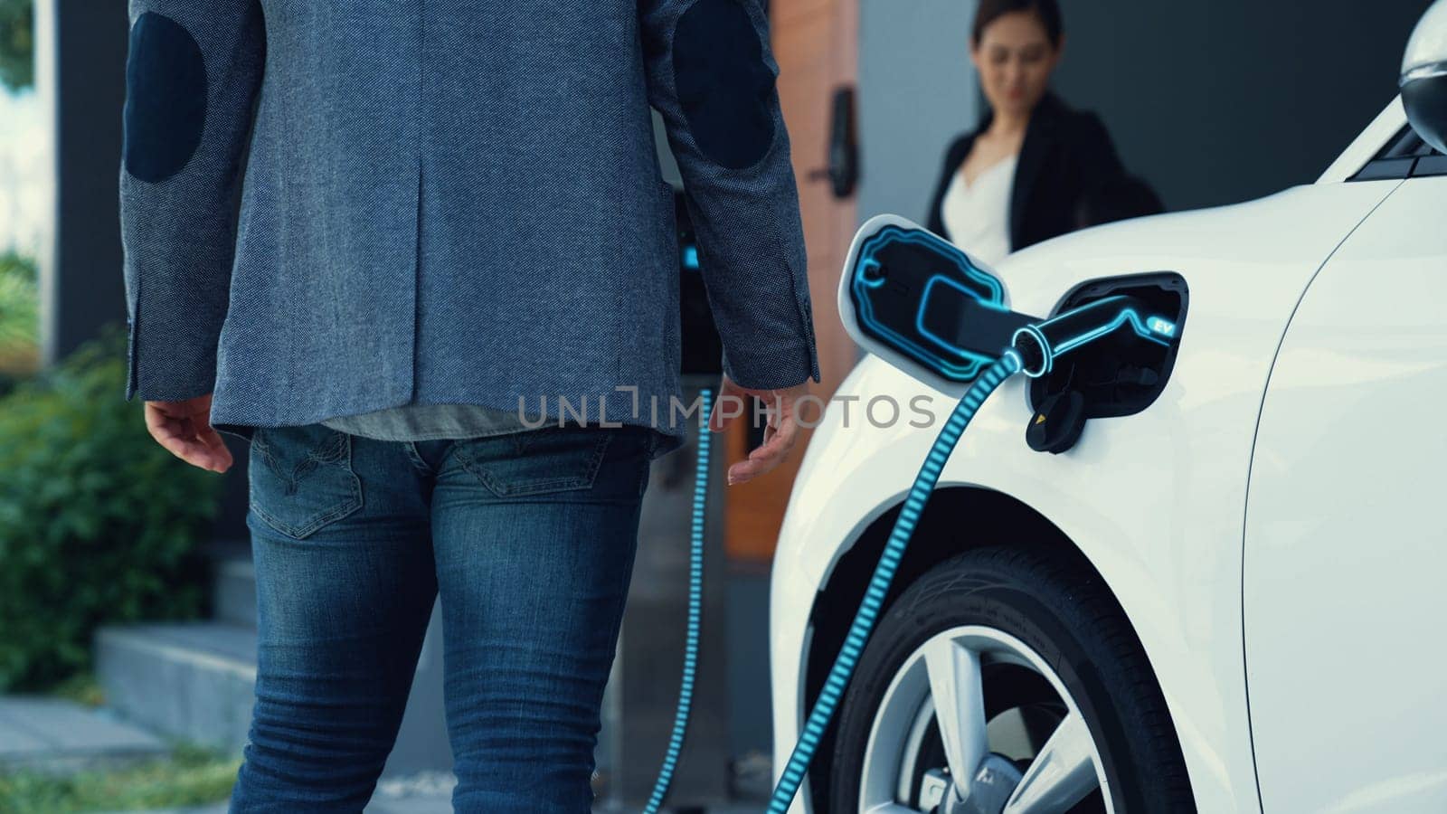 Modern family couple recharge electric car from home charging station. Peruse by biancoblue