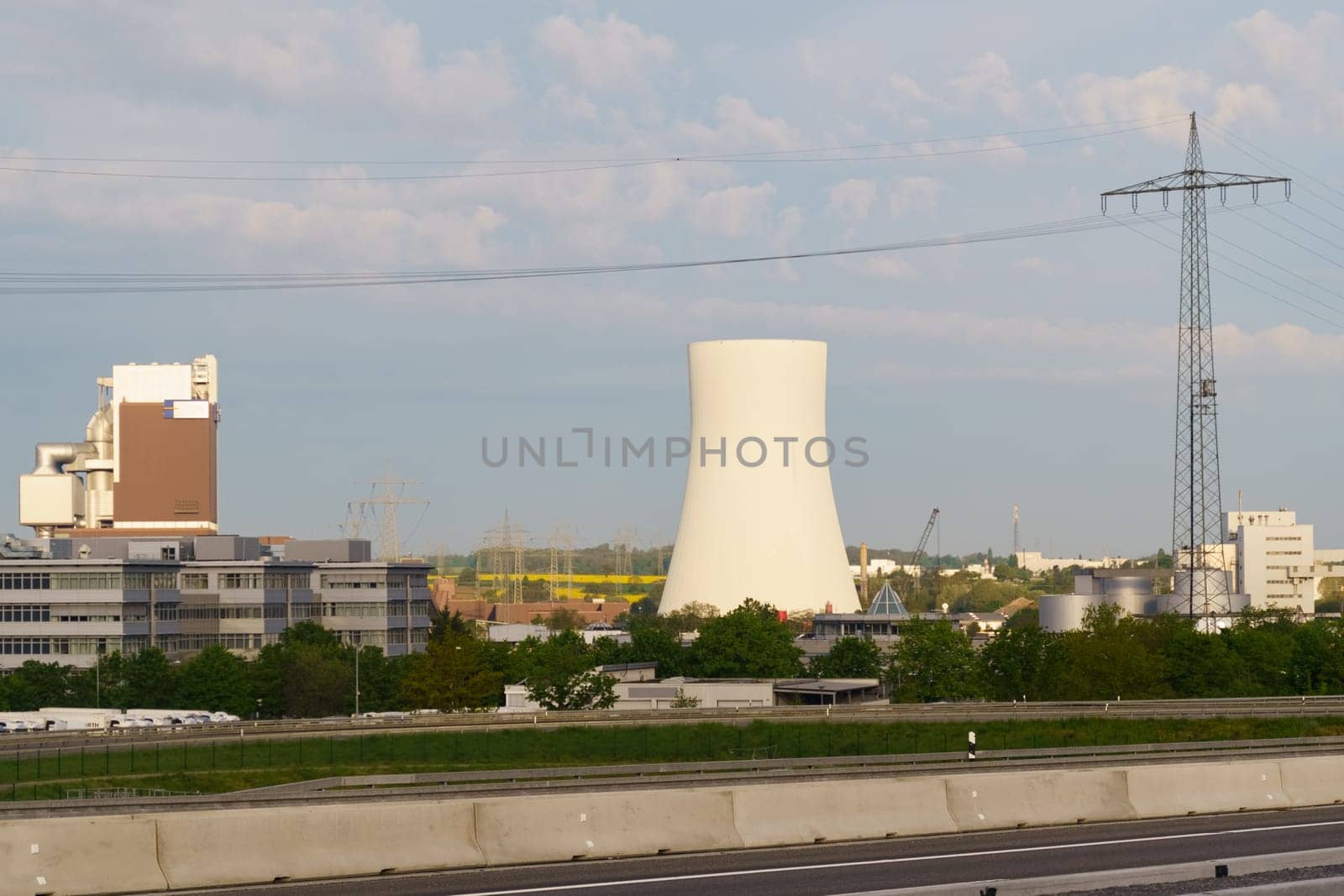 A nuclear power plant stands tall in the background while trees add a touch of nature in the foreground.