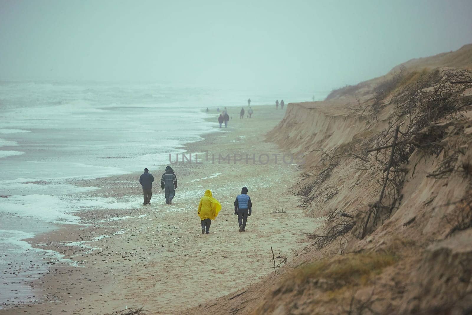 People walk on the beach in stormy weather in Sondervig Denmark.