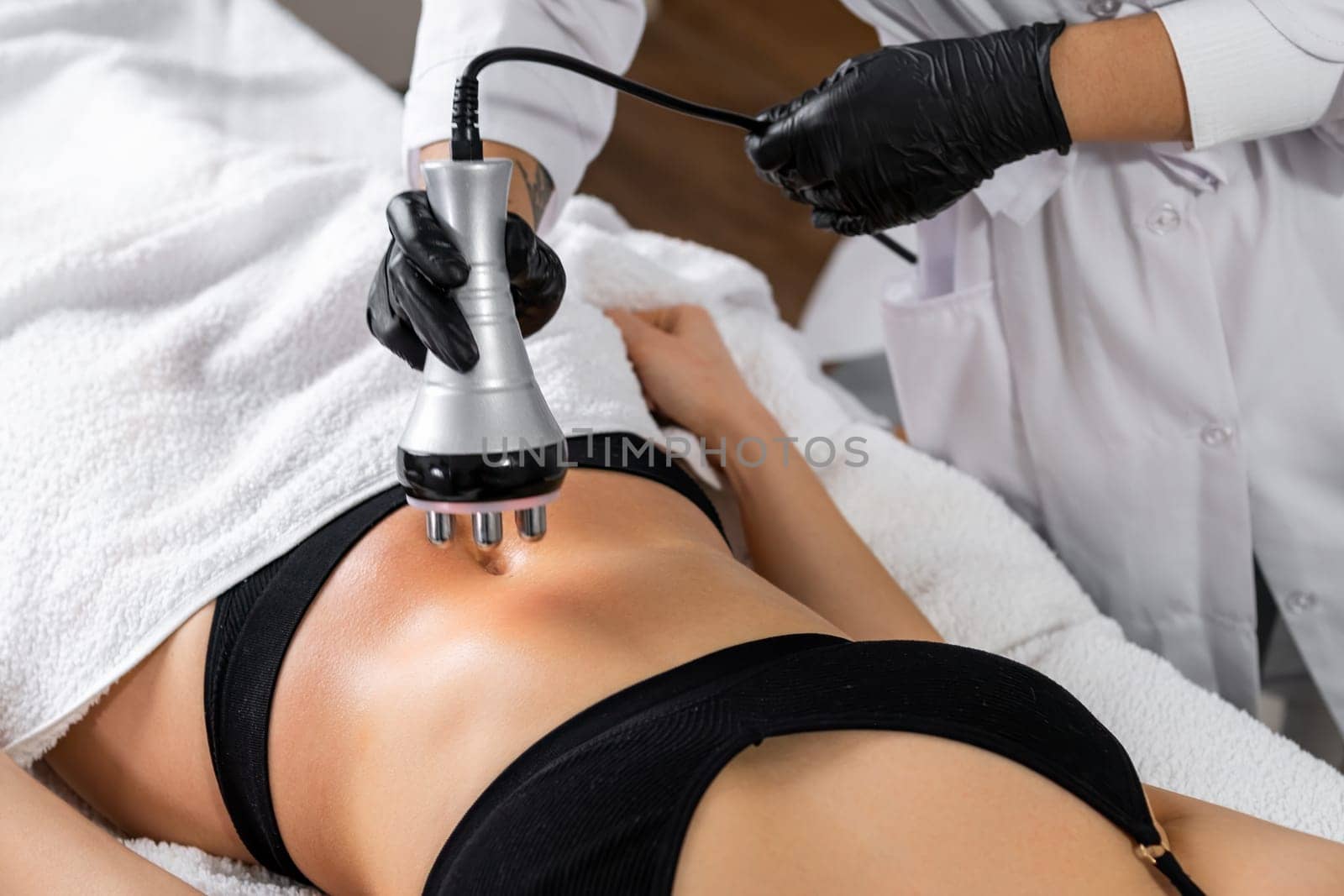 A doctor does the Rf lifting procedure on the stomach of a woman in a beauty salon by vladimka