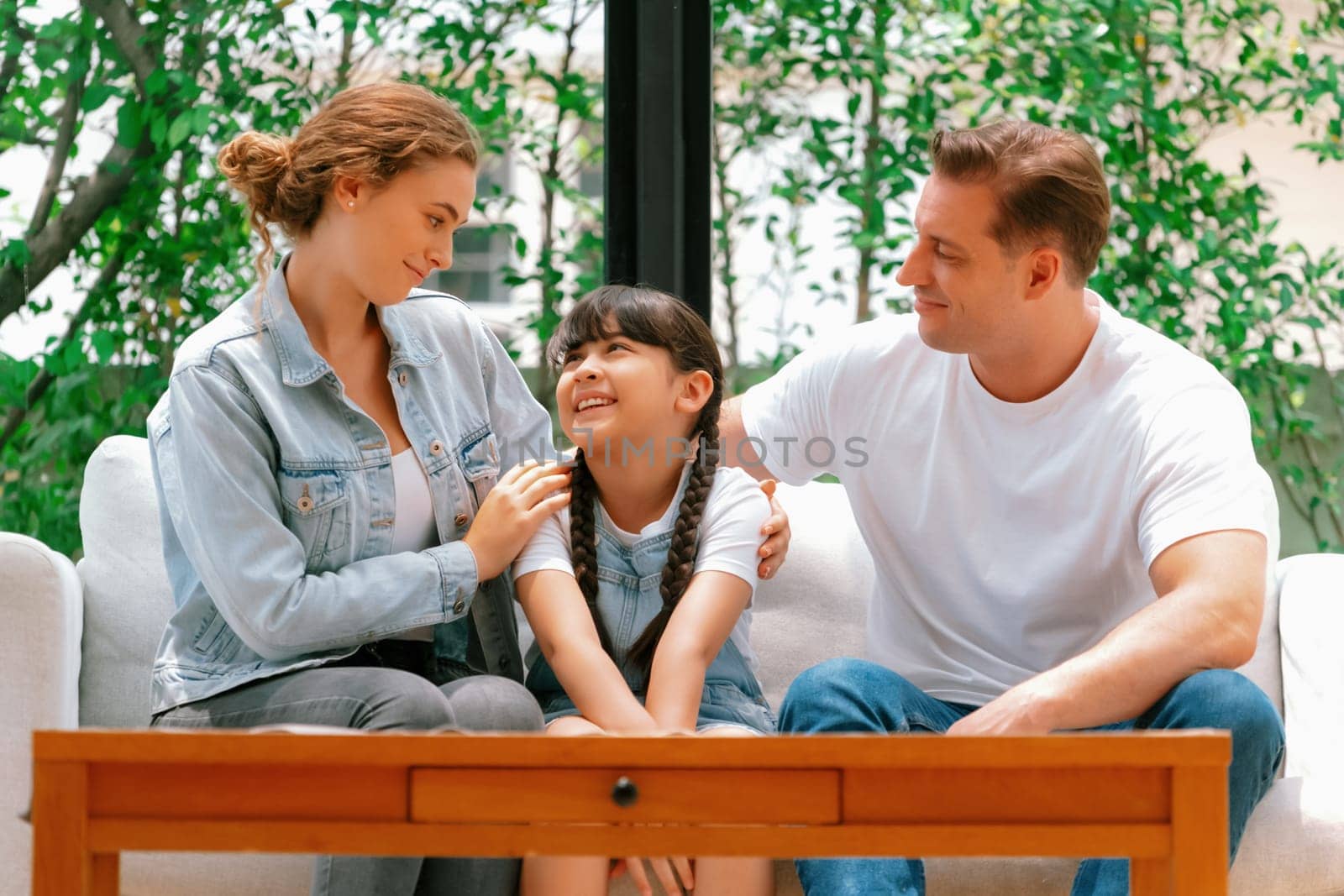 Parents comforting their daughter with loving hug, helping her feel secure and protected from fear, rest her head on shoulder. Happy family love and child care support concept. Synchronos