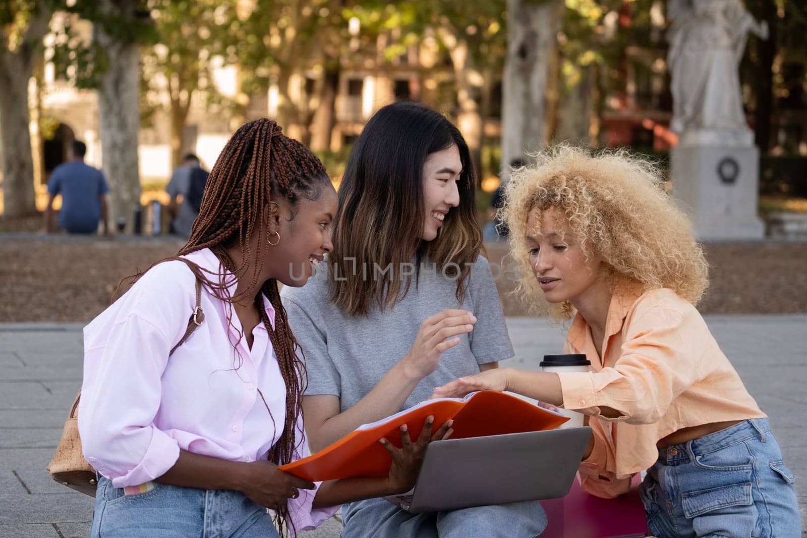 Multiethnic college students are brainstorming regarding homework after class outdoors by papatonic